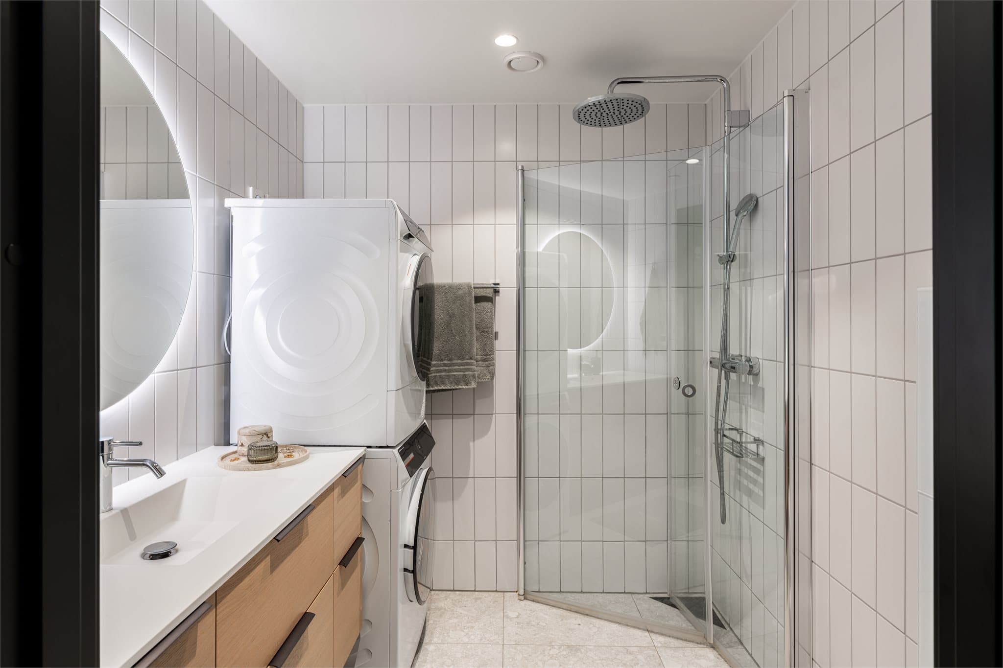 Lyst og romslig bad med flislagte vegger og gulv. Store keramiske terrazzo-inspirerte gulvfliser i lyse gråtoner gir et eksklusivt uttrykk.