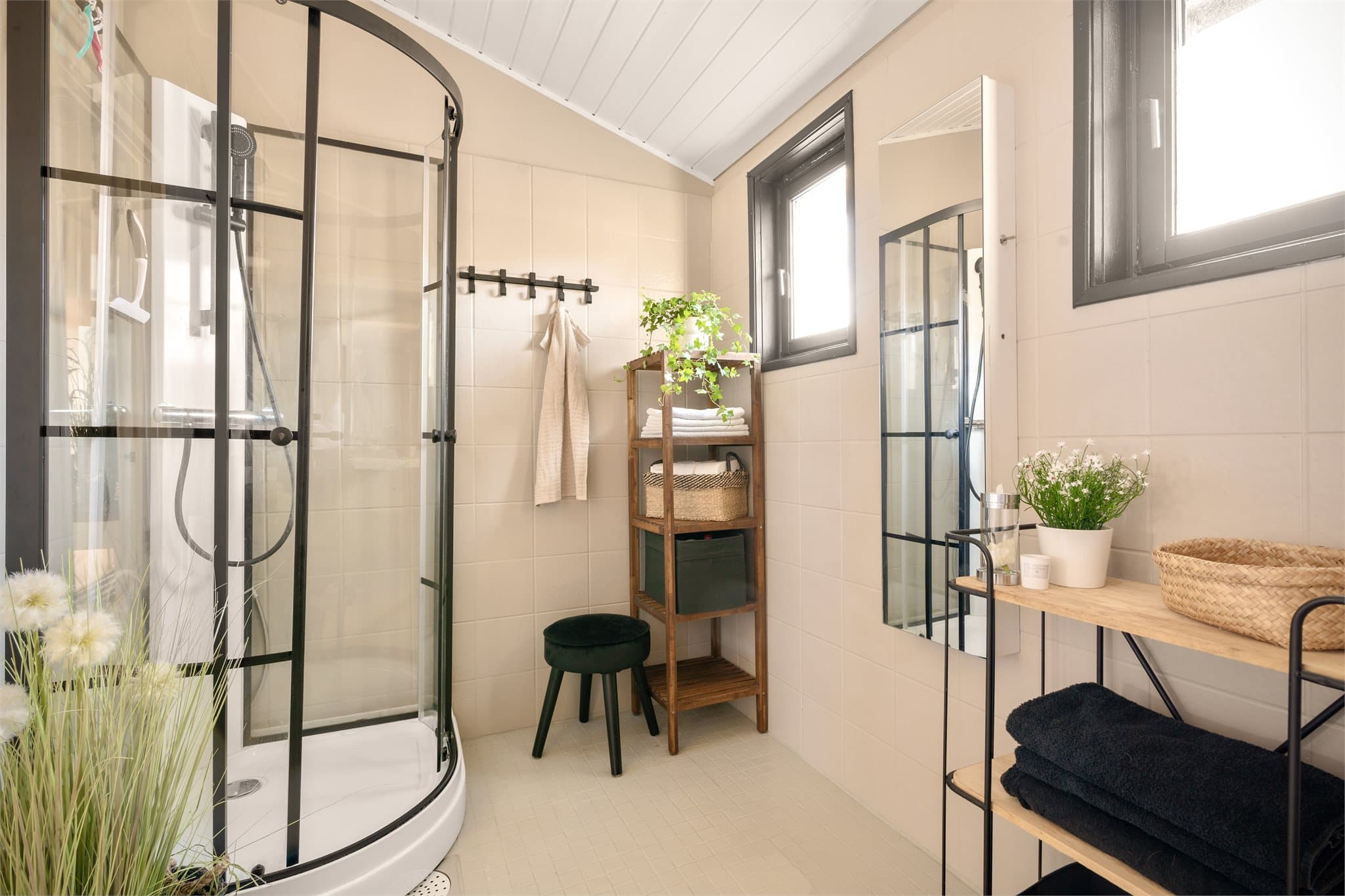 Romslig og funksjonelt baderom med gulvvarme og lyse, malte fliser som gir et rent og moderne uttrykk. Det stilrene dusjkabinettet med sorte detaljer harmonerer fint med resten av interiøret.