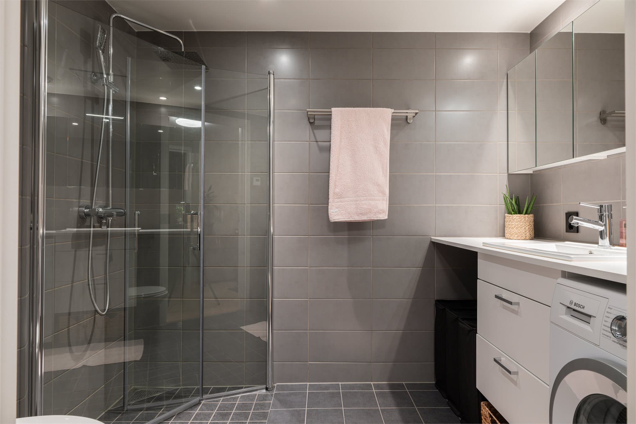 Badet er pent flislagt med grå 20x40 fliser på veggene.