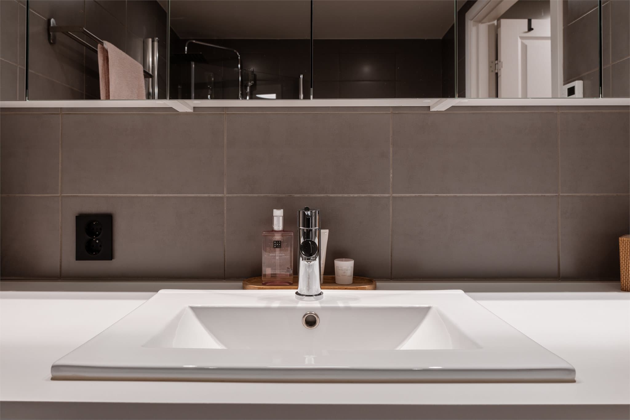 Innredningen består av en hvit servant med tilhørende møbel og et praktisk speilskap.