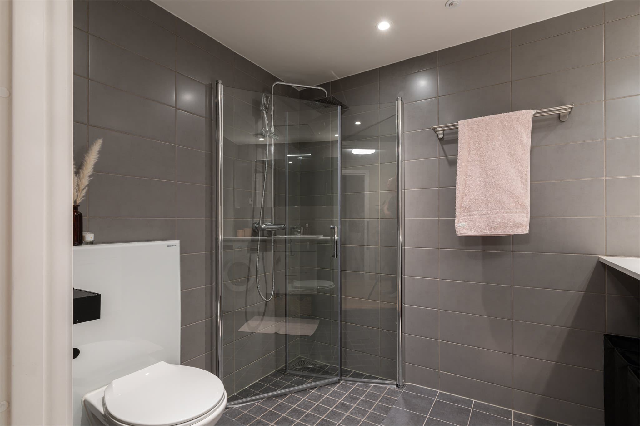 Her er det innfellbare dusjvegger i glass og et vegghengt toalett.