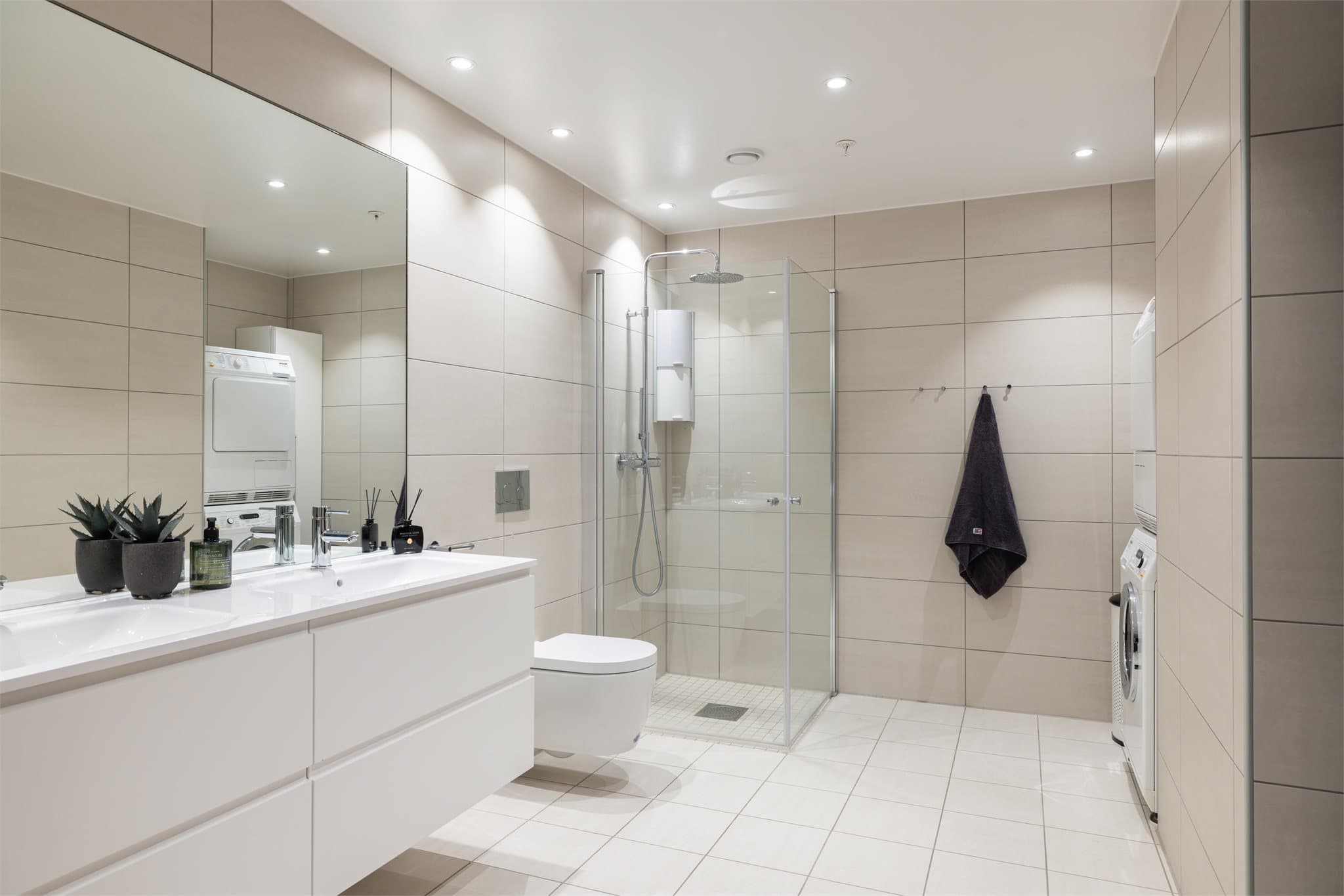 Innredningen består av underskap, servant, speil, vegghengt toalett og dusjhjørne med innfellbare dører.