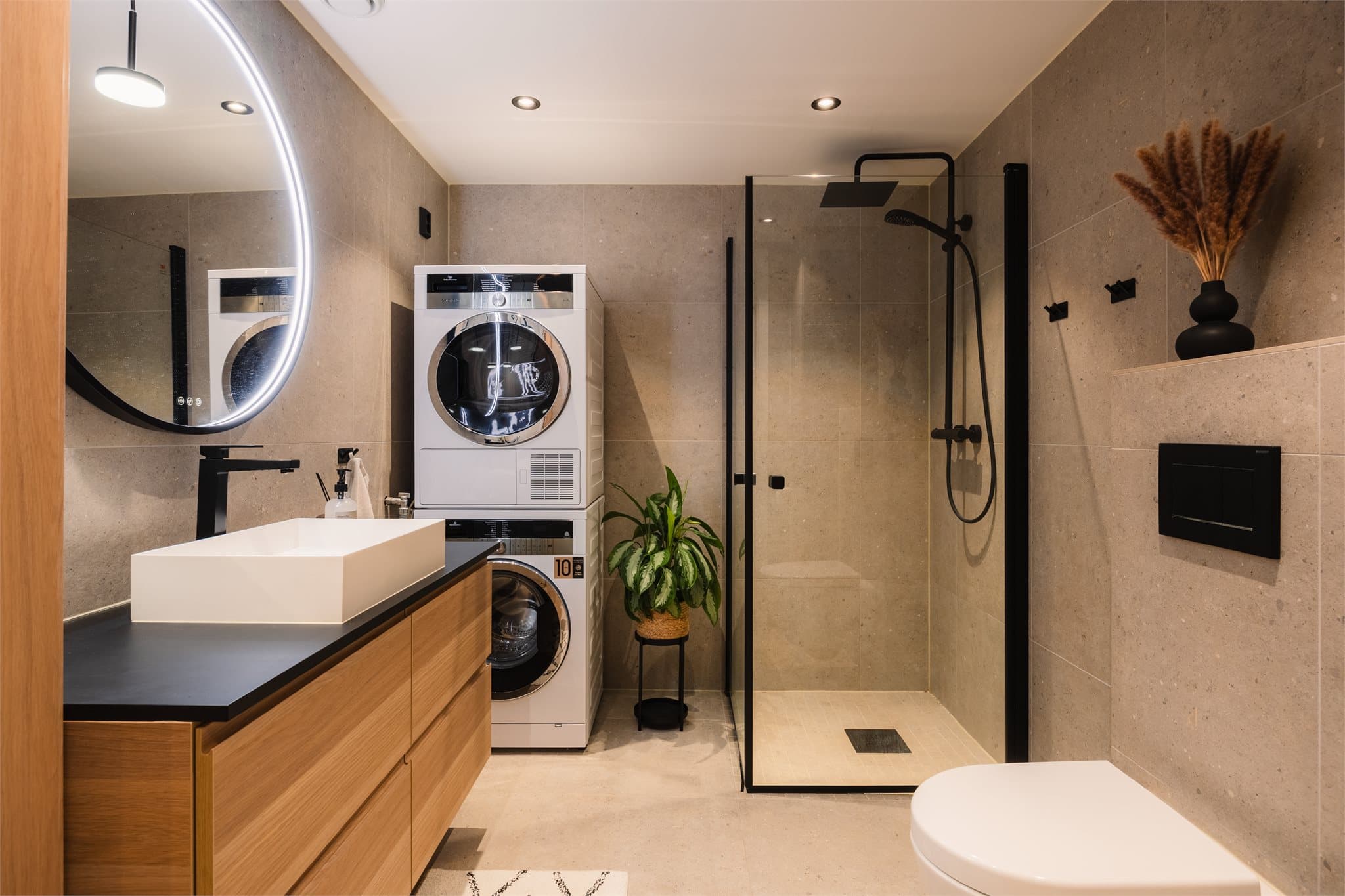 Stilrent og romslig bad med moderne fliser og praktisk opplegg for vaskesøyle.