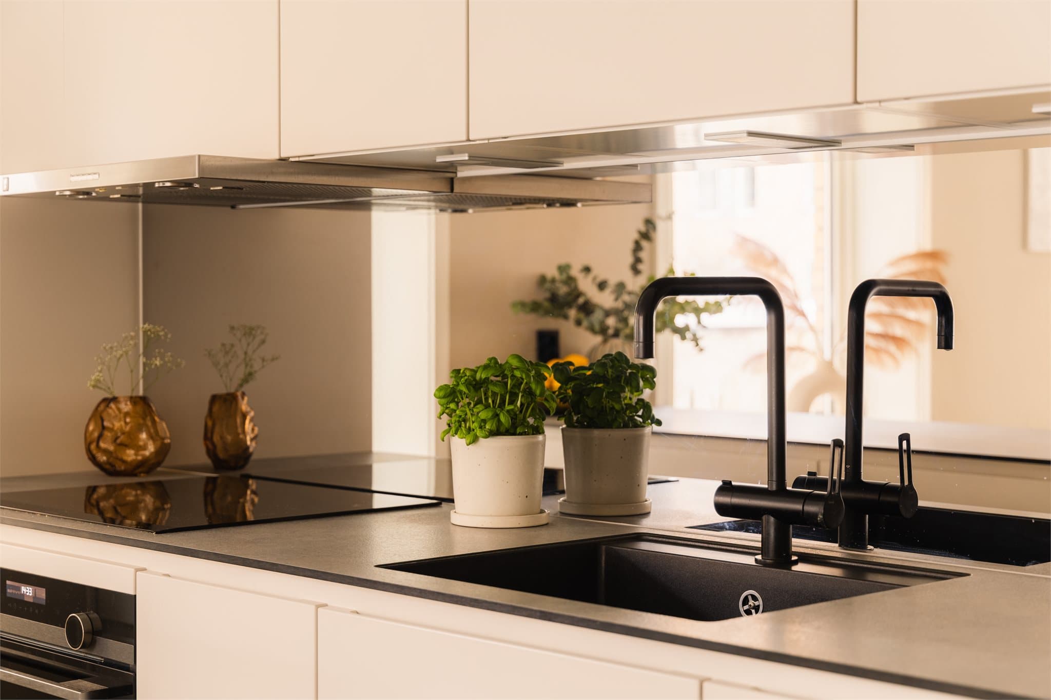 Moderne detaljer med lekker kontrast - sort armatur, underlimt vask og integrert platetopp.