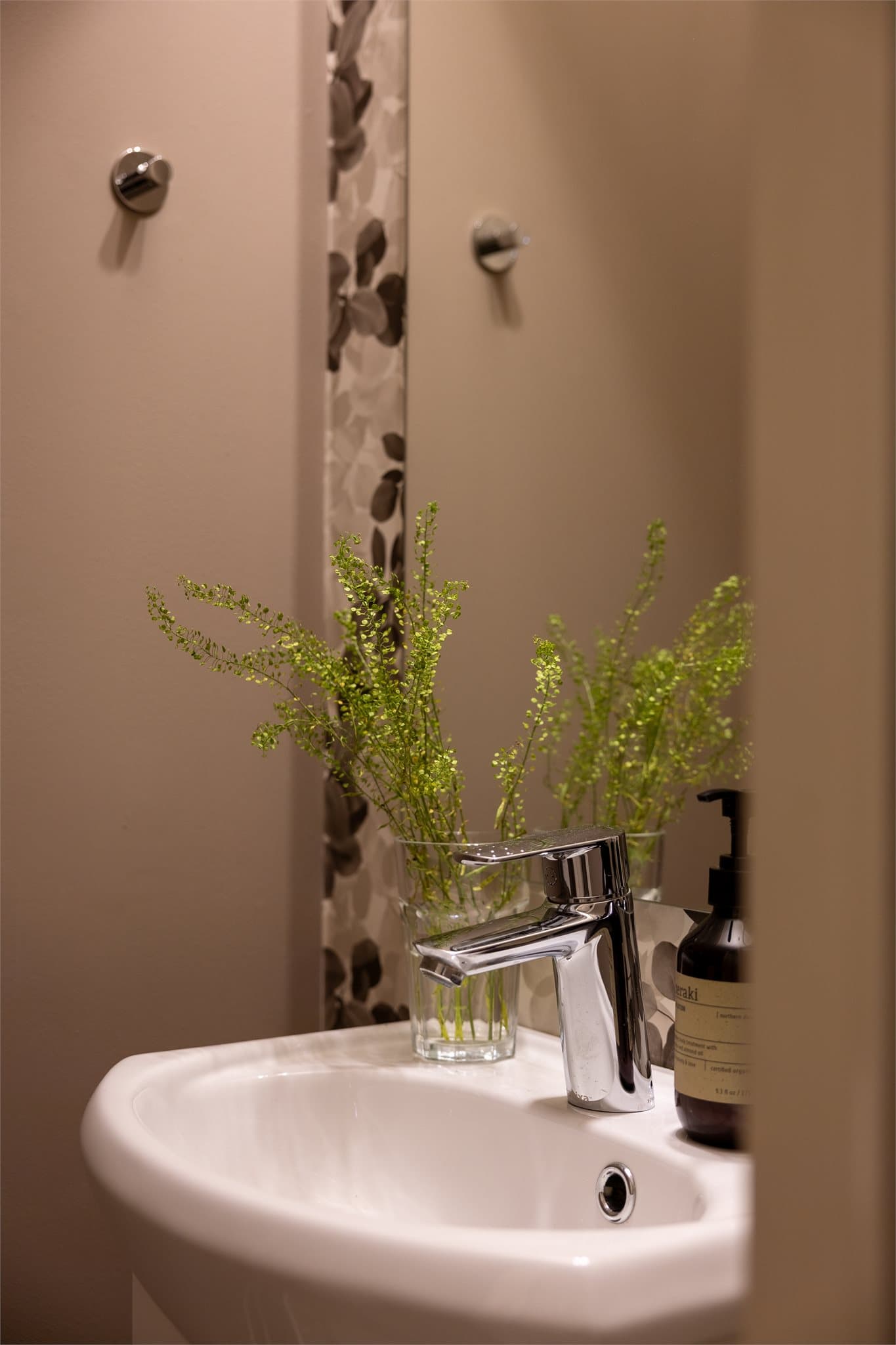 Toalettrommet har mønstret tapet og vinylbelegg på gulv.