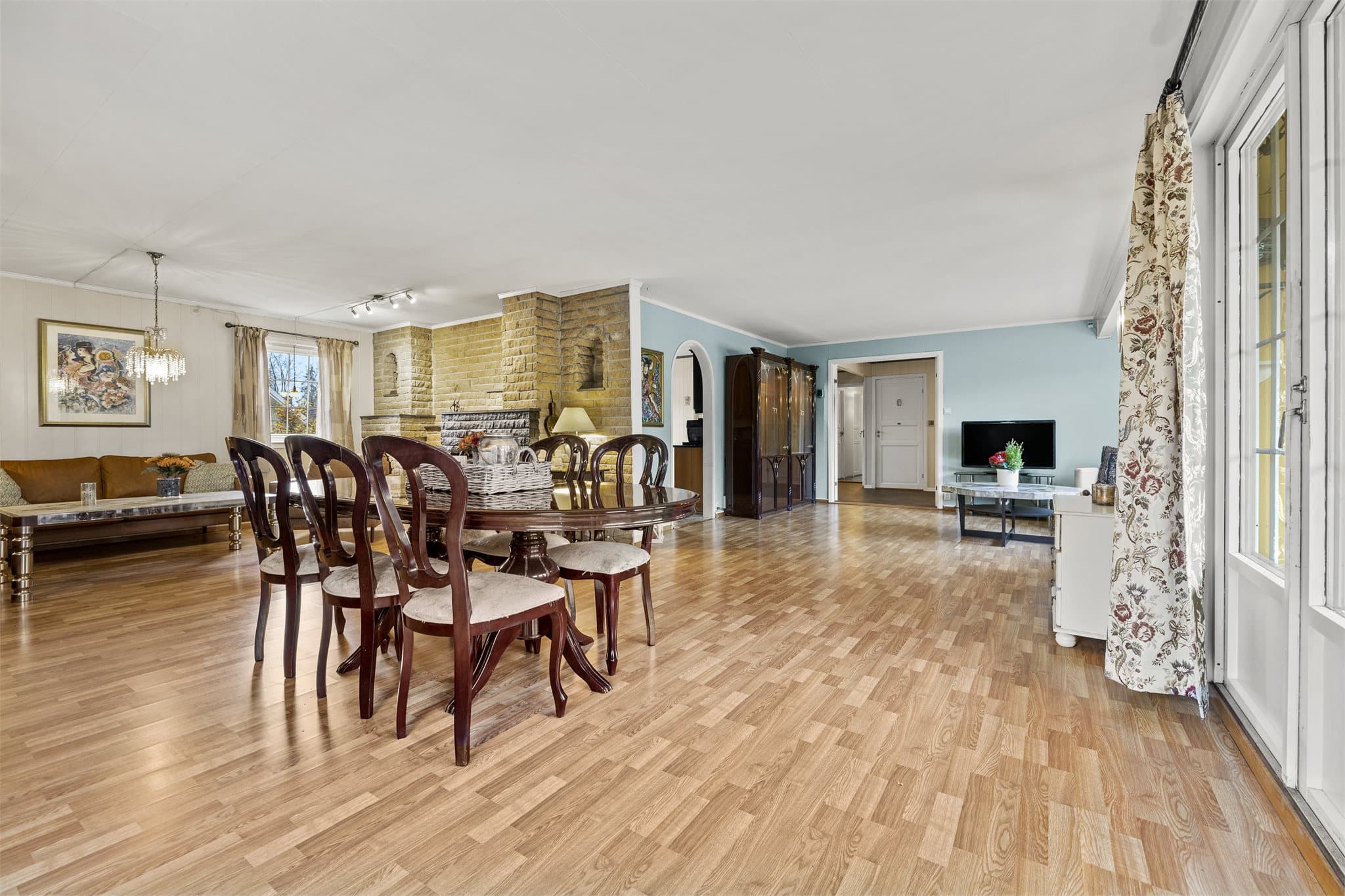 Den lyse stuen har god plass til både sofagruppe og spiseplass, og store vinduer slipper inn rikelig med dagslys.