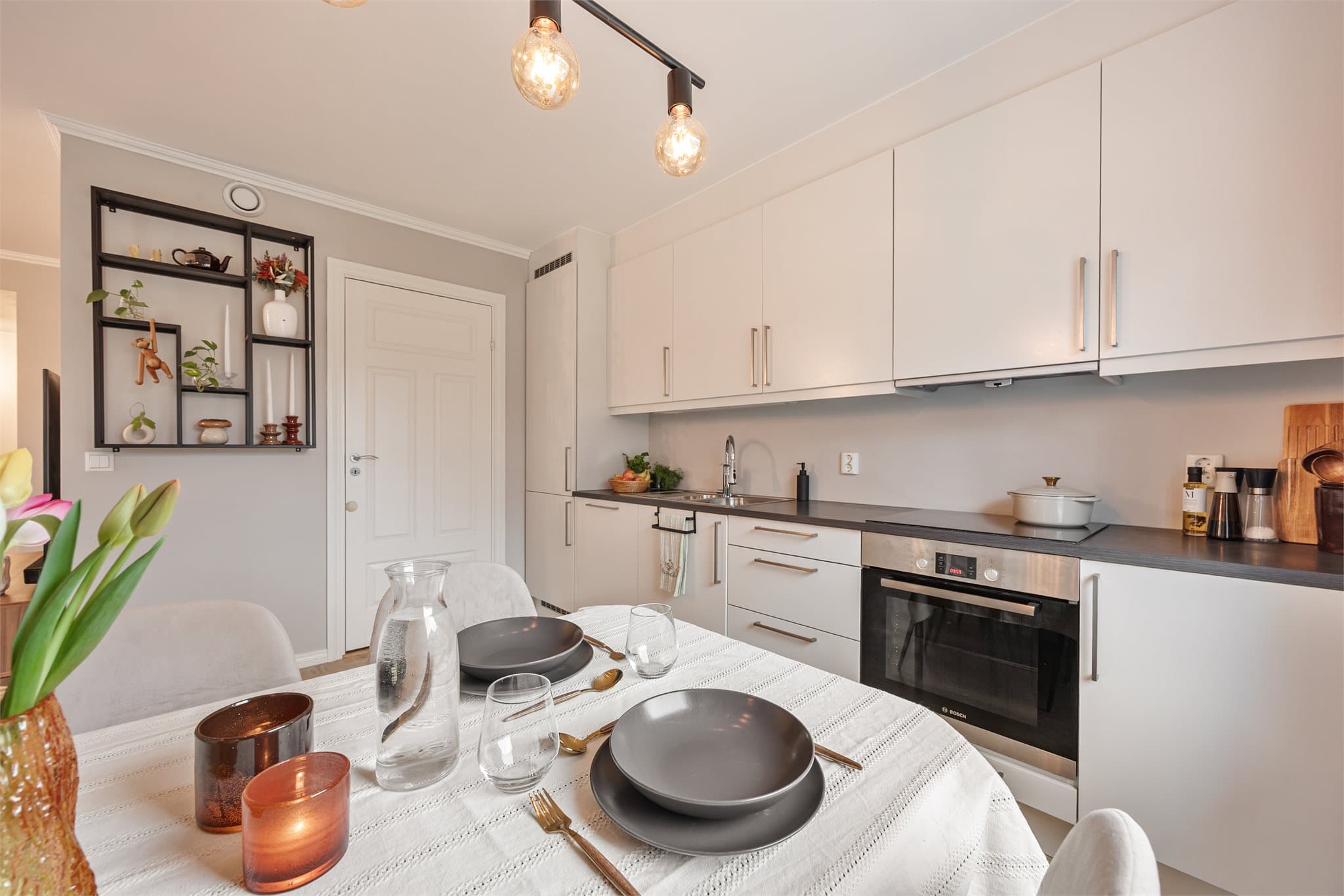 Kjøkkeninnredningen har hvite, slette fronter og laminat benkeplate.