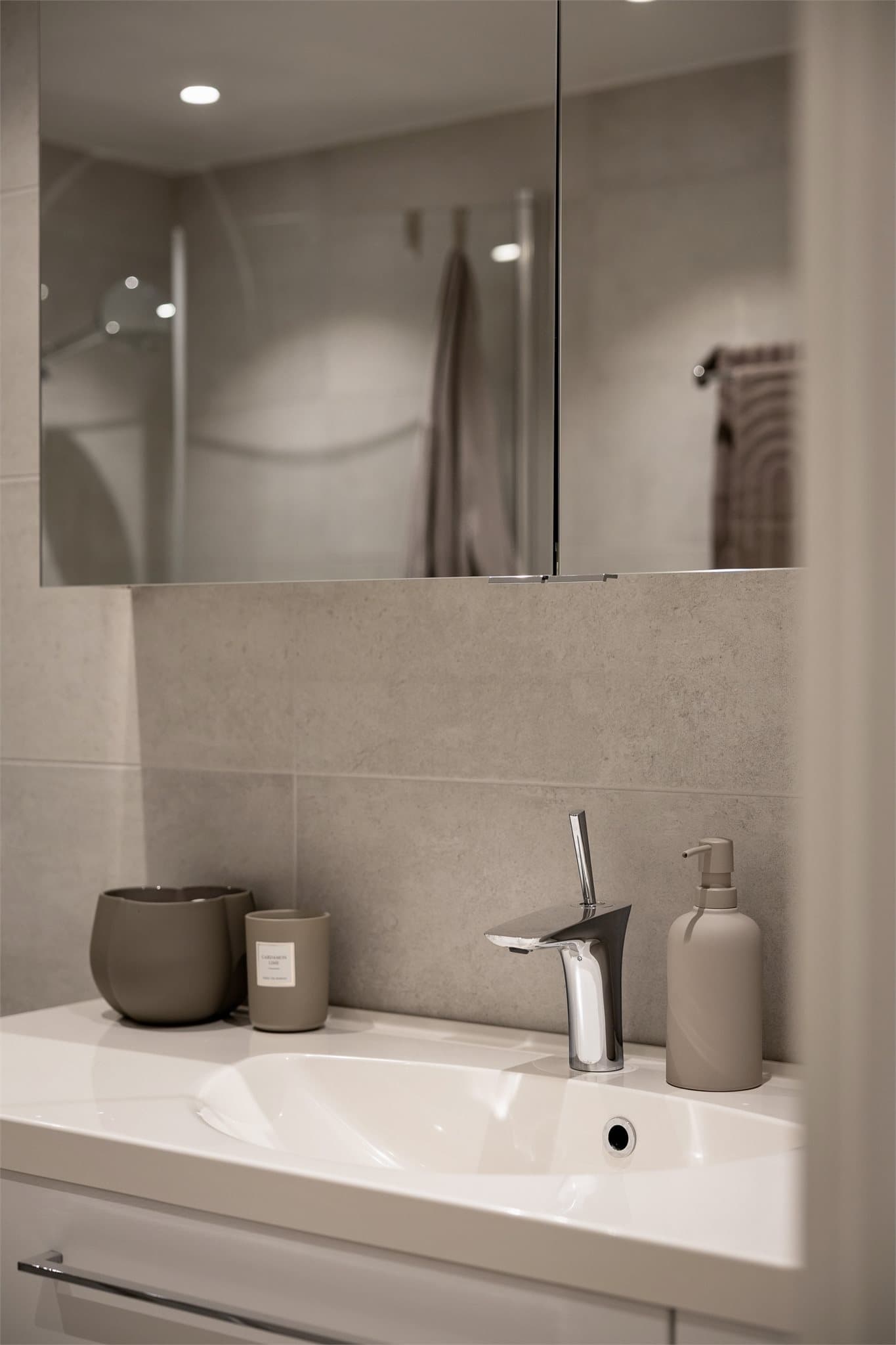 Baderomsinnredning med overskap med speil, toalett og dusjhjørne med innfellbare dusjvegger i glass