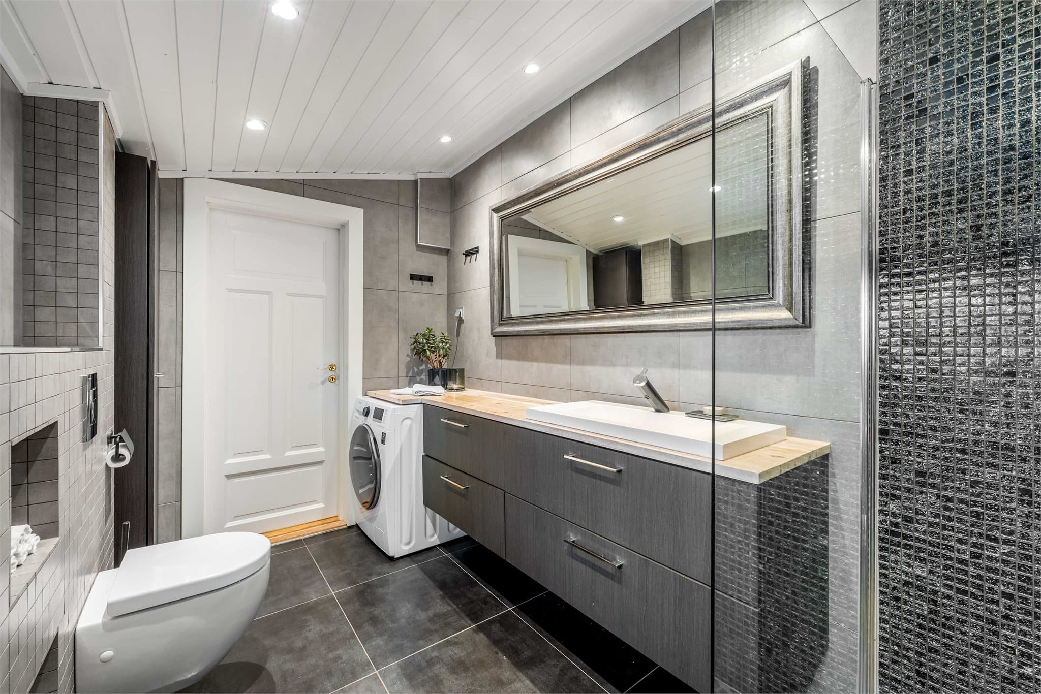 Rommet er helfliset med panel og downlights i himling. For ekstra komfort er det termostatstyrt gulvvarme.