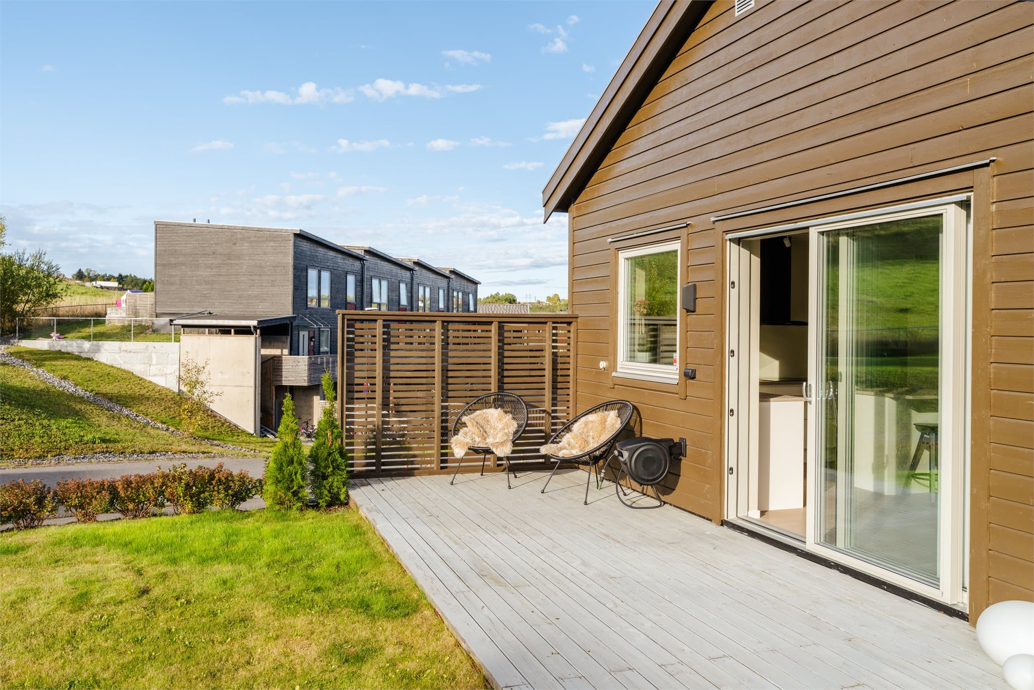 Skjermet markterrasse med spilerekkverk og utgang fra kjøkkenet.