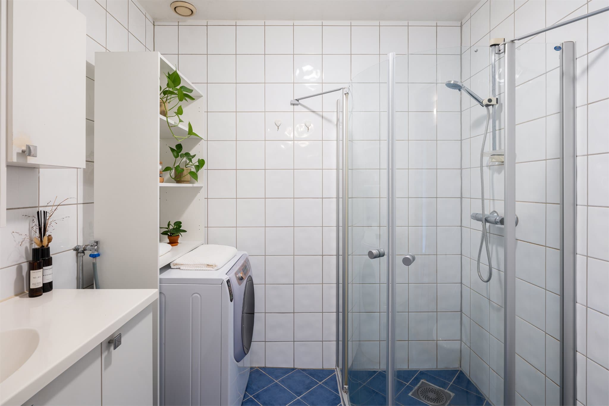 Flislagt bad med elektriske varmekabler og opplegg for vaskemaskin.