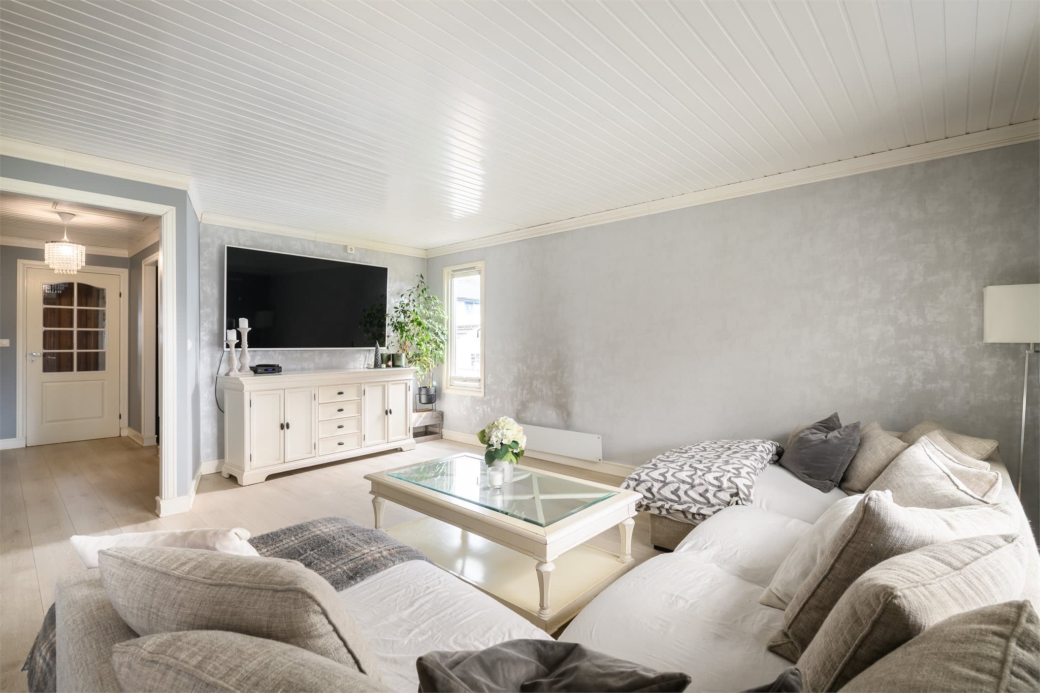 Dagslyset strømmer inn via store vinduer i to himmelretninger.