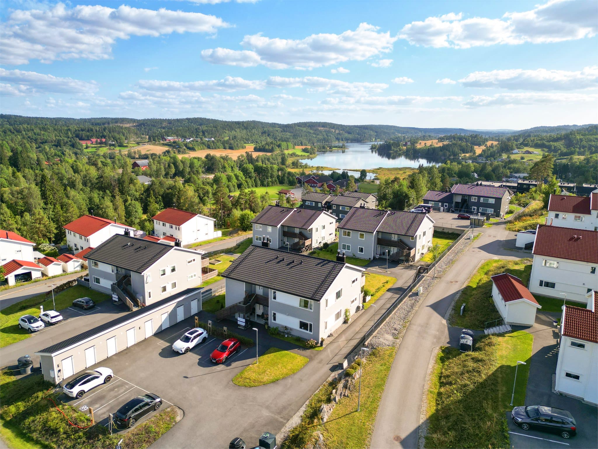 Fra luften får du et godt inntrykk av boligens beliggenhet og uteområdene, med egen parkeringsplass med ladeboks og praktiske sportsboder samlet i rekke like ved boligen.