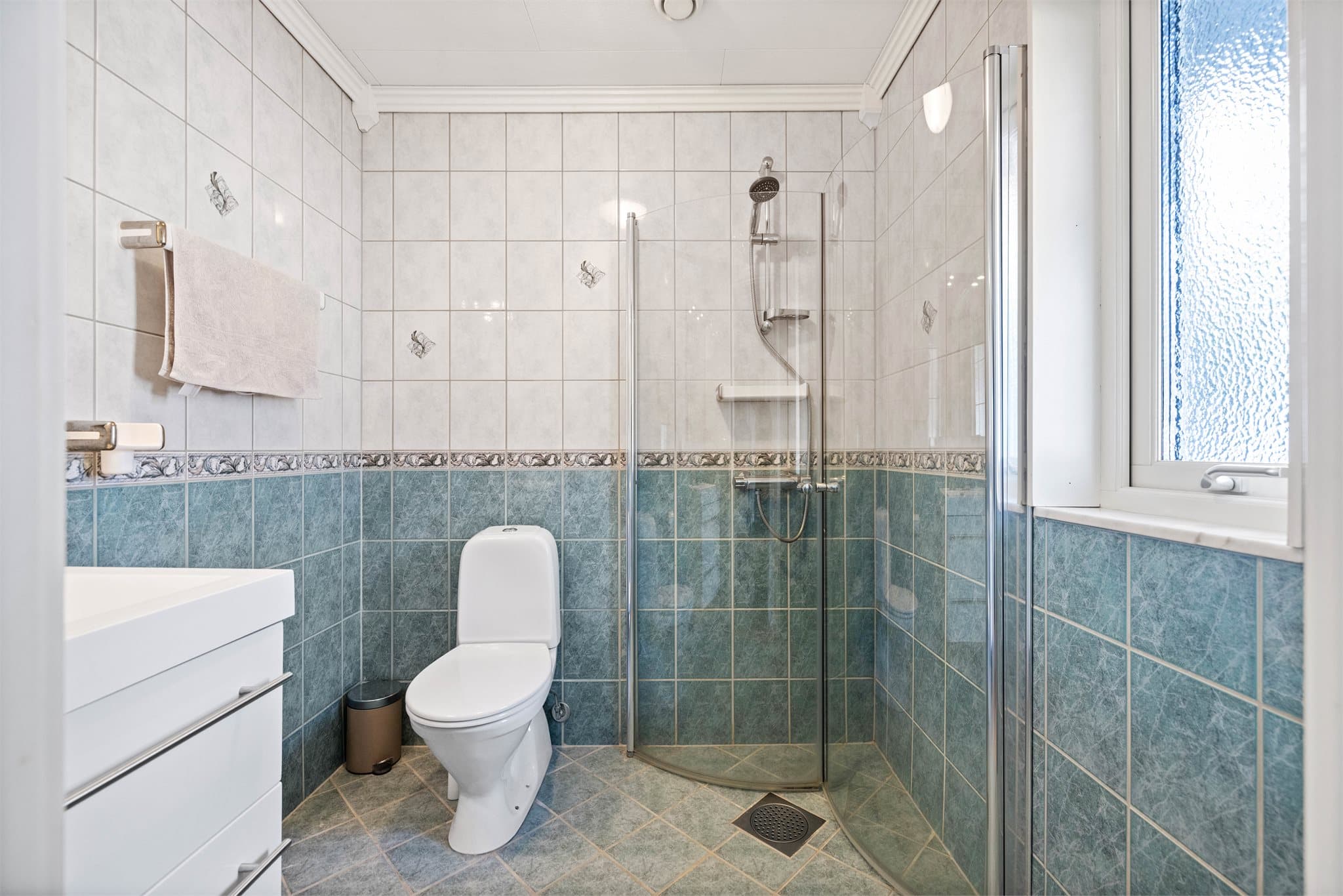 Flislagt bad med vindu som gir naturlig lys.