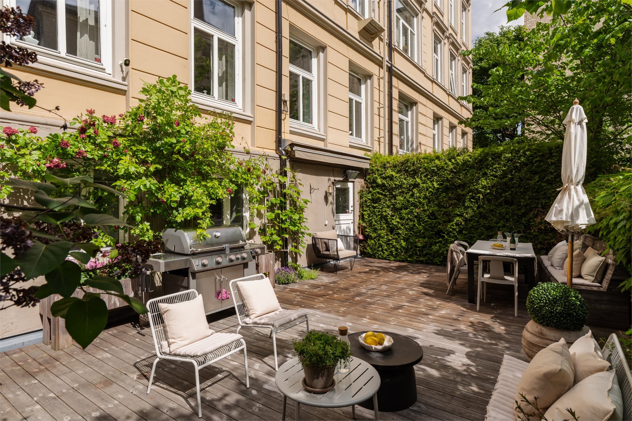Terrassen fremstår som en grønn oase med flotte beplantninger bestående av hekker, syriner, klatreroser og vindruer som skaper en lun og skjermet atmosfære.