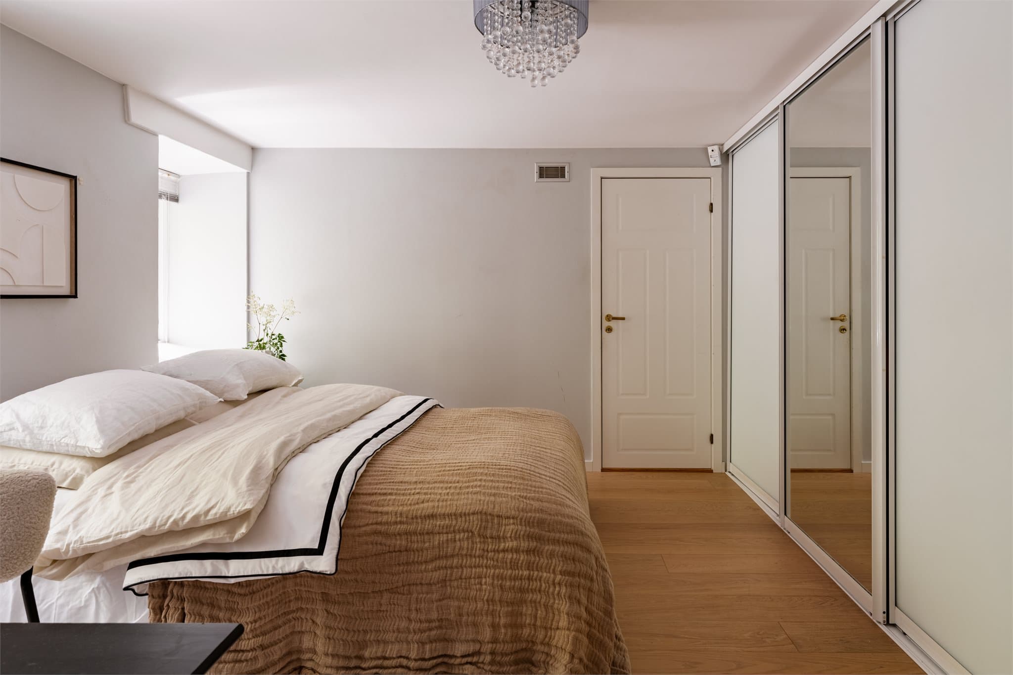 En stor skyvedørsgarderobe strekker seg langs den ene veggen og gir rikelig med oppbevaringsplass, mens boligens innvendige bod er praktisk tilknyttet rommet.