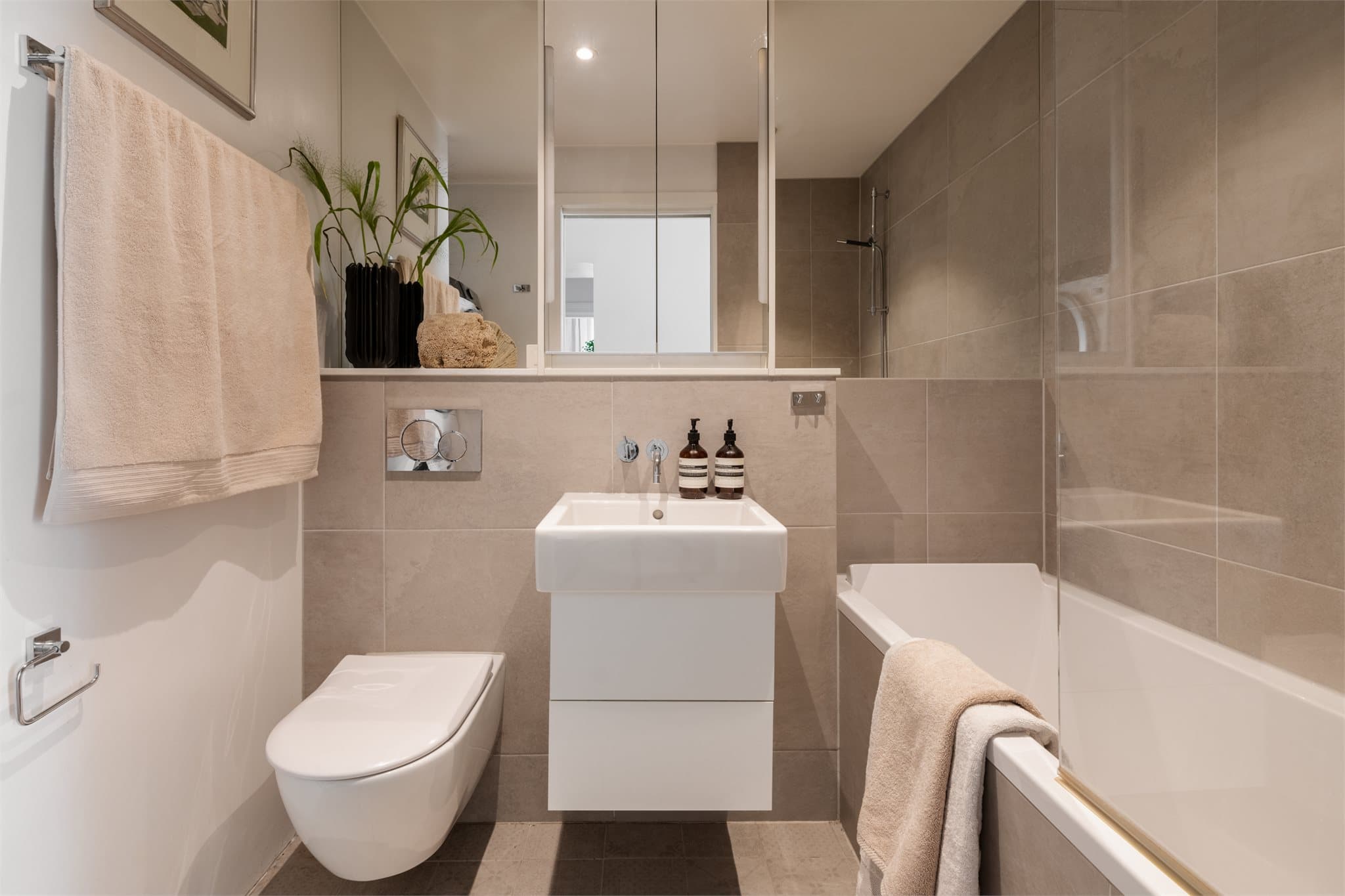Hovedbadet (2017) og fremstår moderne og funksjonelt med tidløse materialvalg. Badet er innredet i elegante beige og hvite toner, og downlights i taket gir en behagelig belysning. Flislagte gulv med varmekabler sørger for god komfort året rundt.