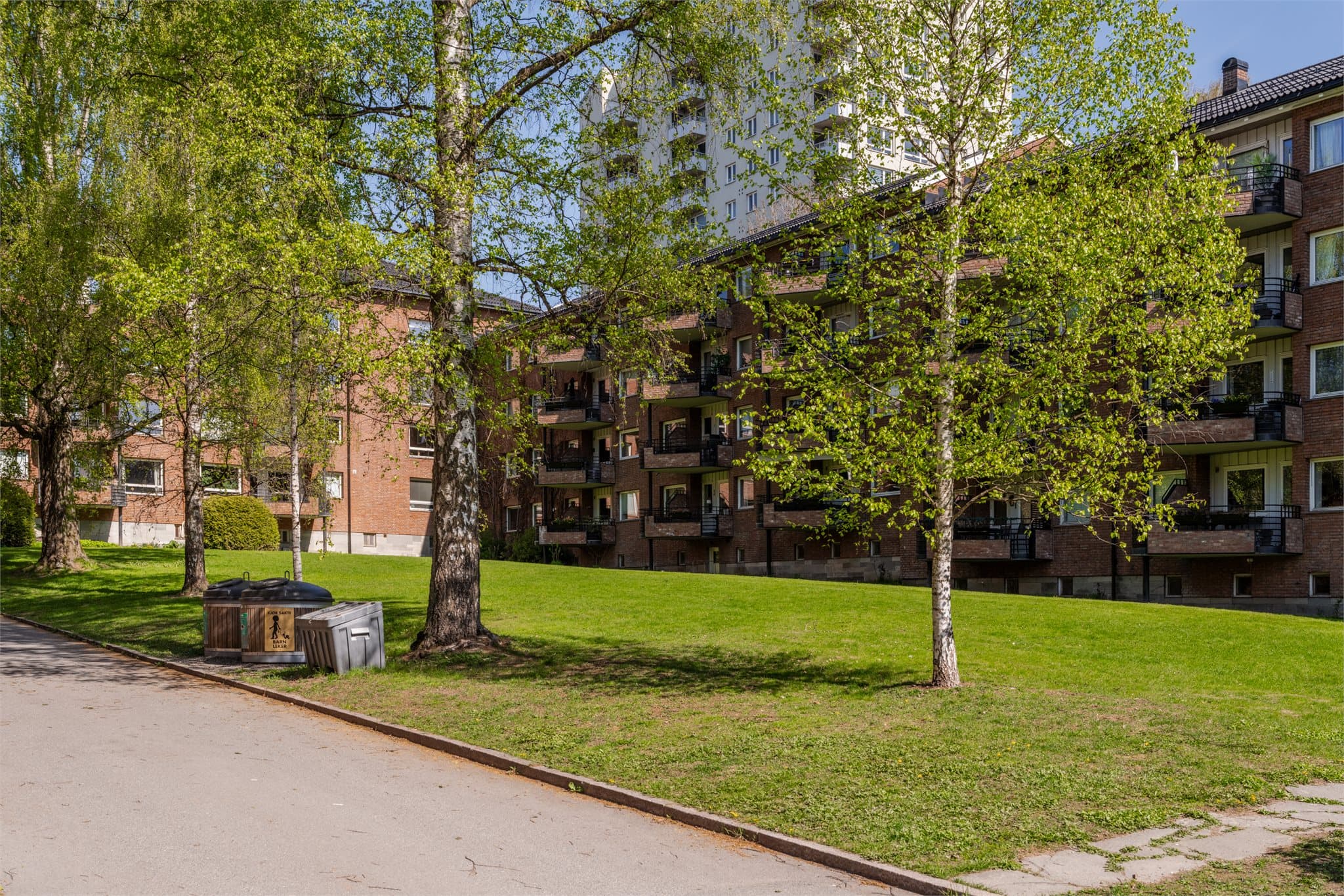 Like bak leiligheten ligger et lite parkområde med bålpanne.