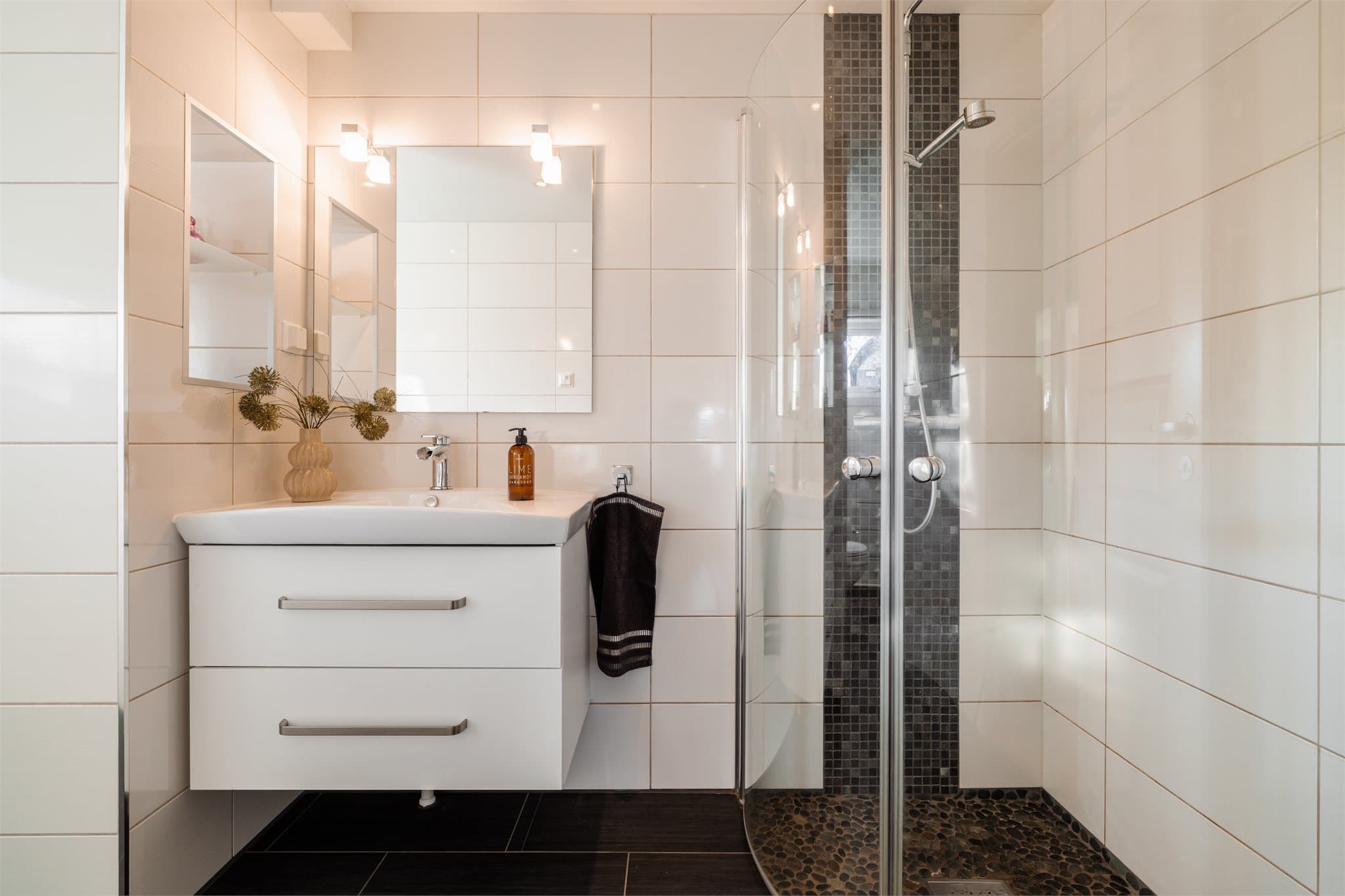 Badet er innredet med servantskap med glatte, folierte fronter og heldekkende servant, samt speil på veggen over servanten.