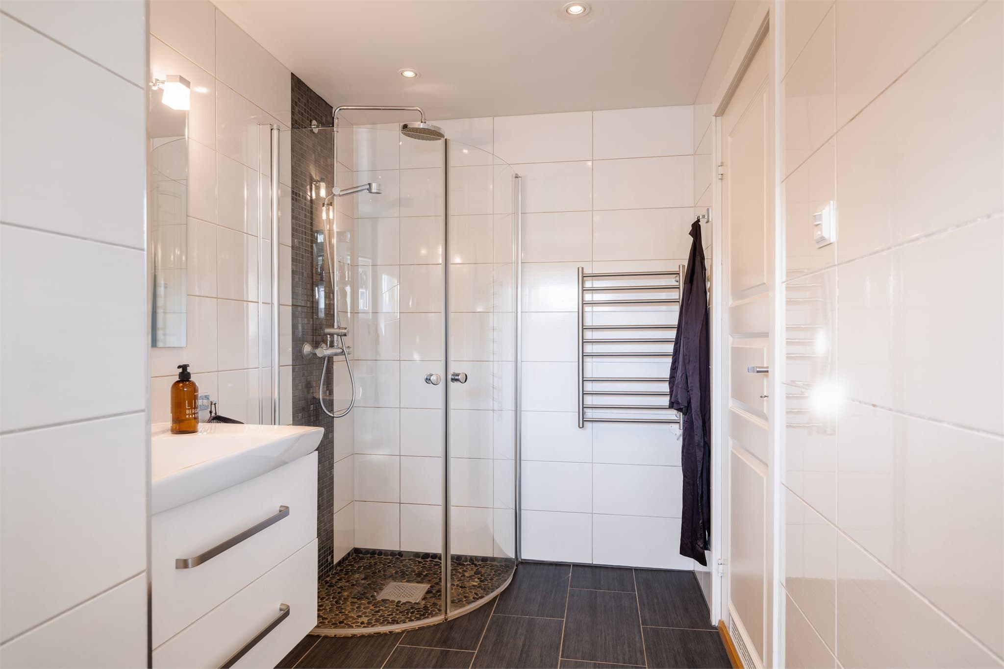 Videre er det tilkoblet opplegg for vaskemaskin, veggmontert toalett samt dusjhjørne med svingdører, håndholdt dusj og termostatstyrt blandebatteri. Badet har avtrekk i veggen.