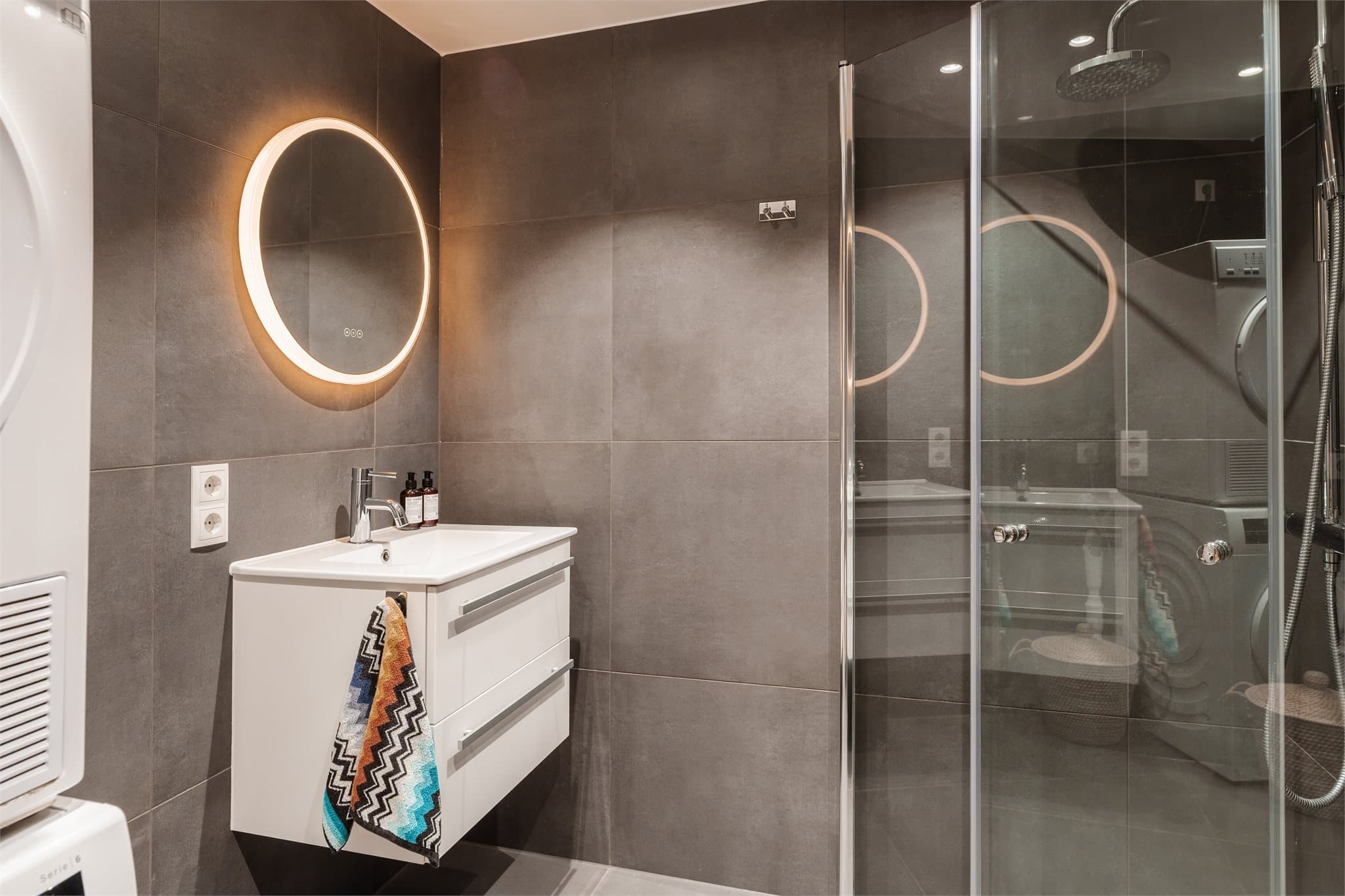 Videre er badet utstyrt med servant med skuffeinnredning, samt vegghengt klosett med innebygget sisterne. Det er også opplegg for vaskemaskin