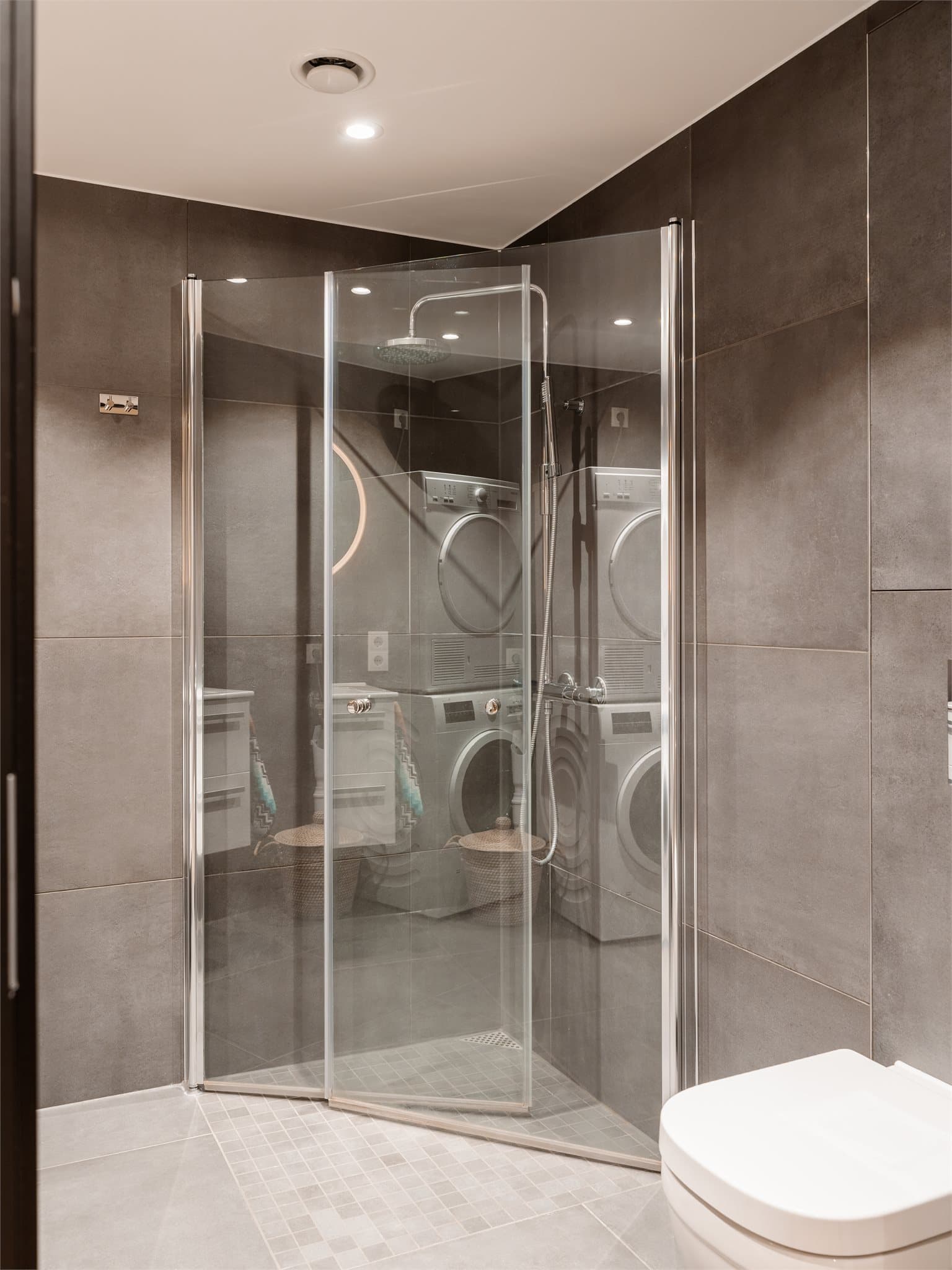 Det er dusj på gulv med dusjdører i herdet glass