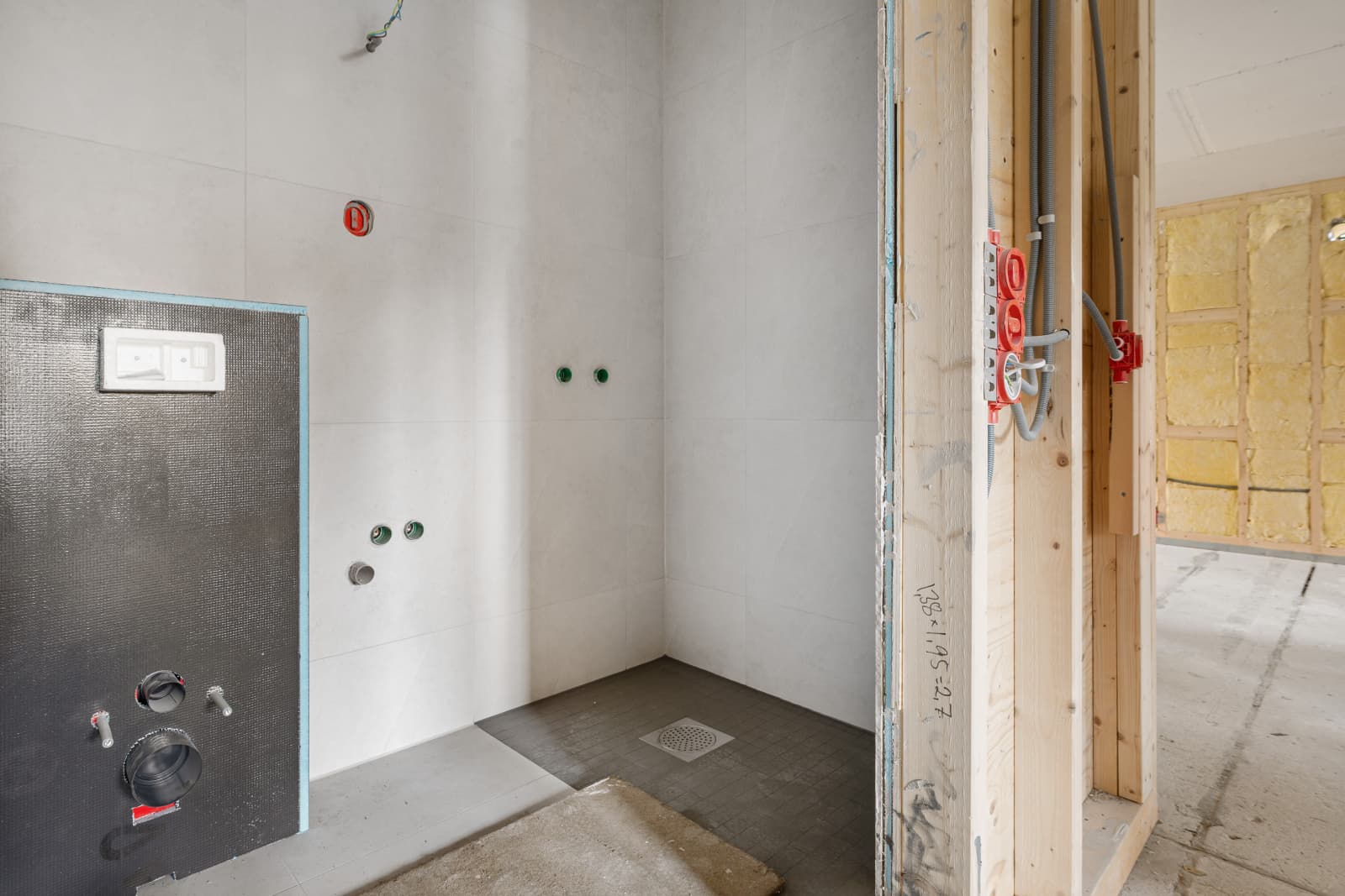 Påbegynt baderom nr. 1 store moderne flisvalg med mindre fliser i dusjsonen, tilrettelagt for vegghengt wc.