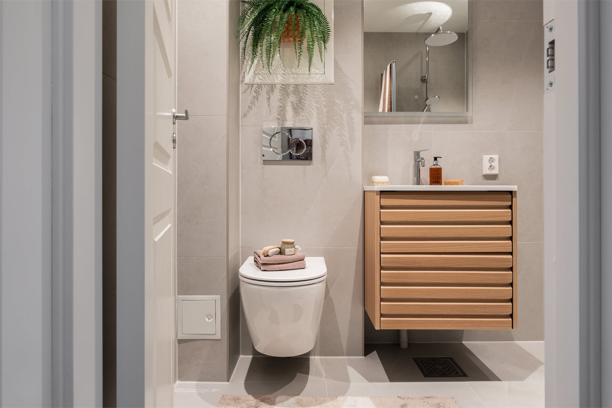 Delikat, flislagt bad med vegghengt toalett og en moderne baderomsinnredning.