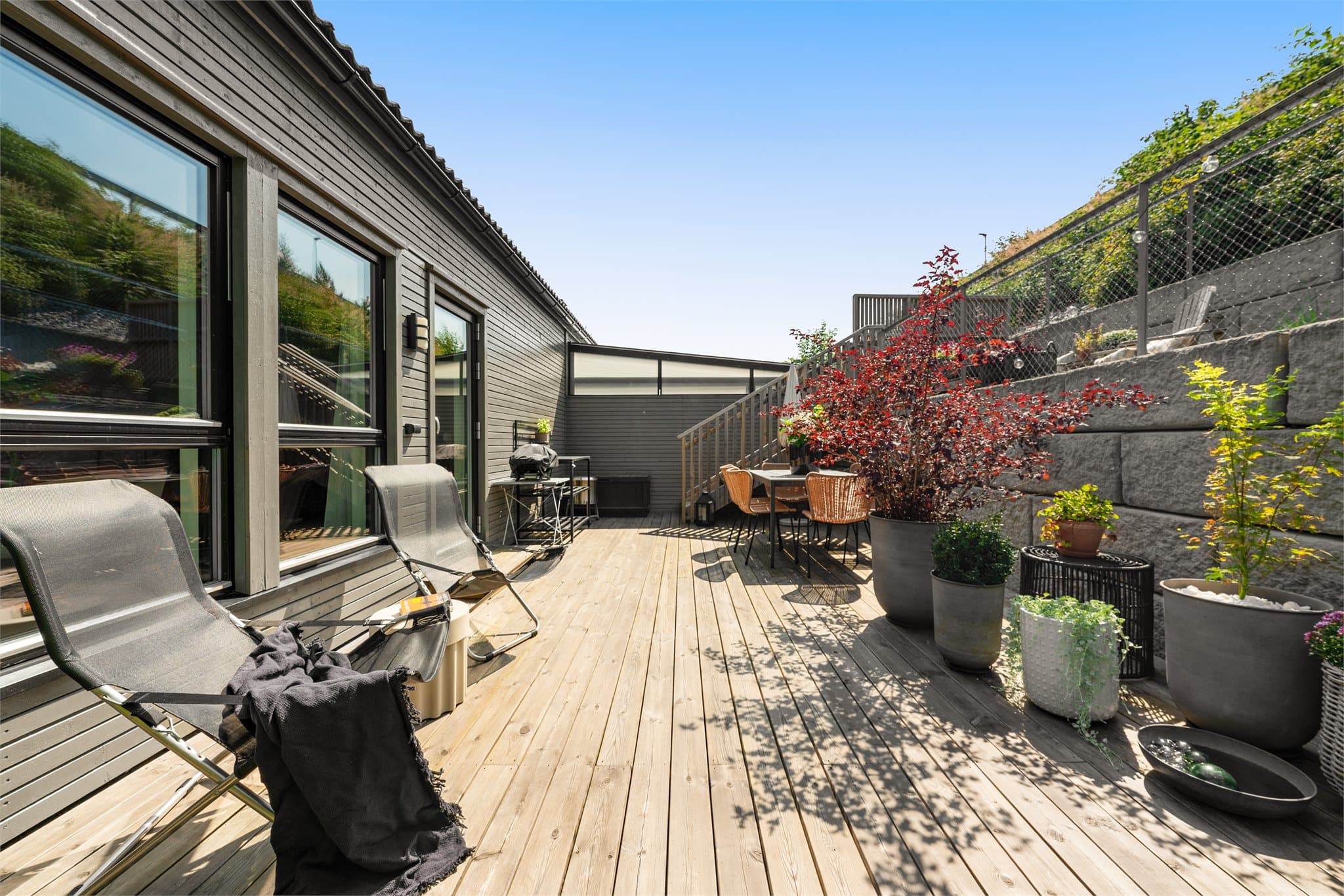Stor platting med plass til flere sittegrupper og trapp opp mot den andre hageetasjen.