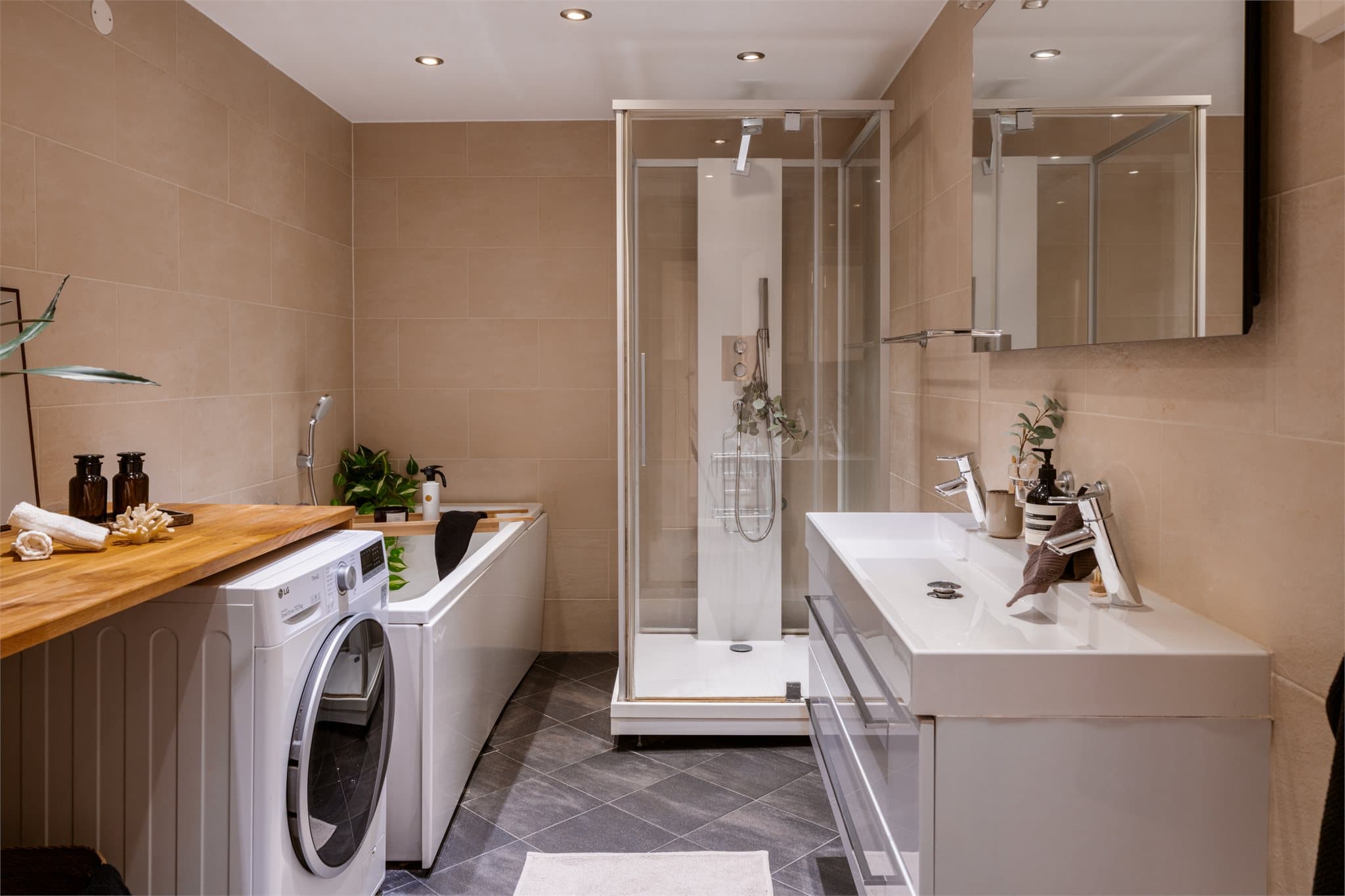 Stort og delikat flislagt bad, utstyrt med både badekar og dusjhjørne.