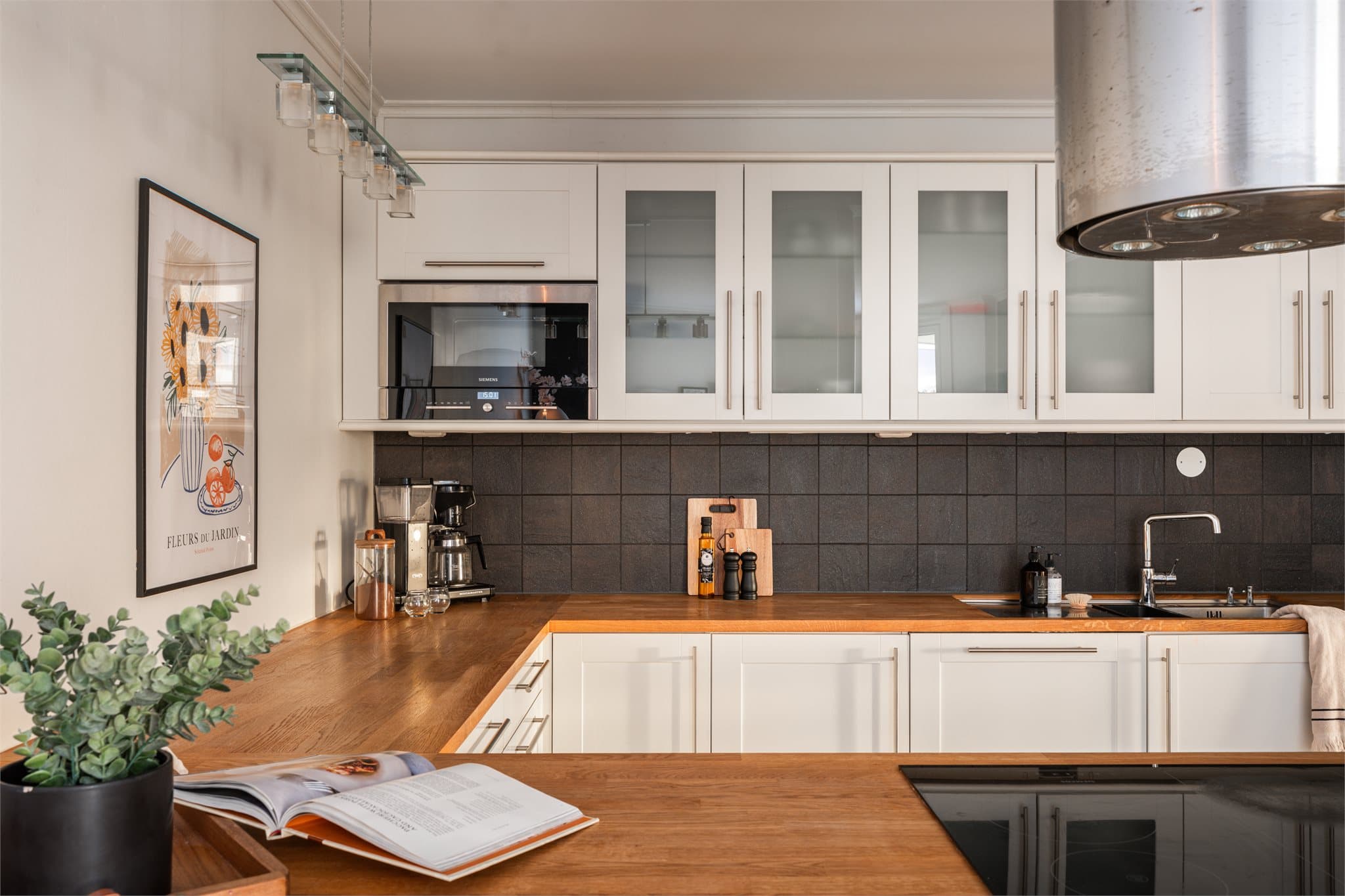 Kjøkkeninnredningen har profilerte fronter, vitrineskap og en solid benkeplate i tre.