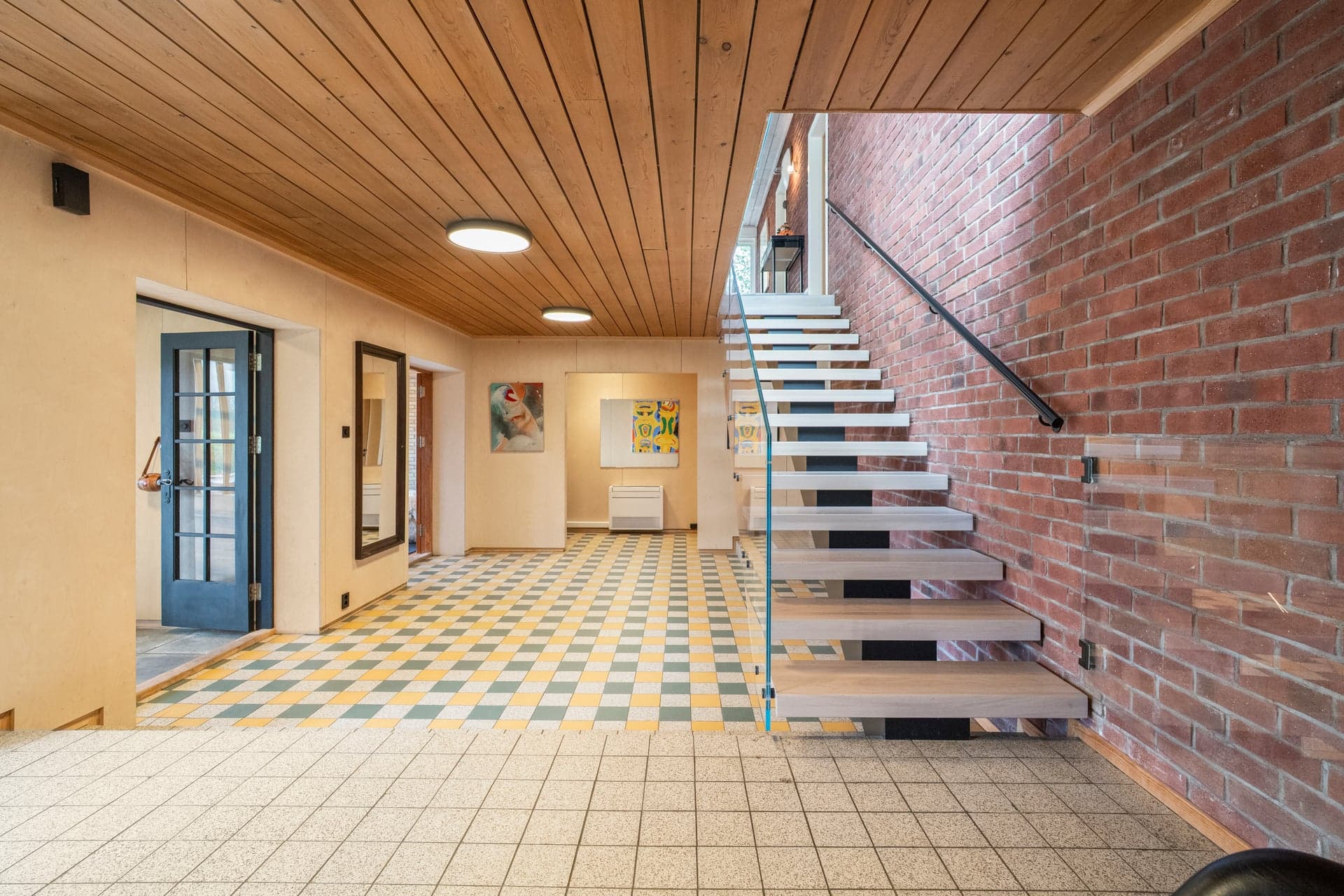 Videre fører en moderne og elegant trapp med glassrekkverk opp til hovedetasjen.