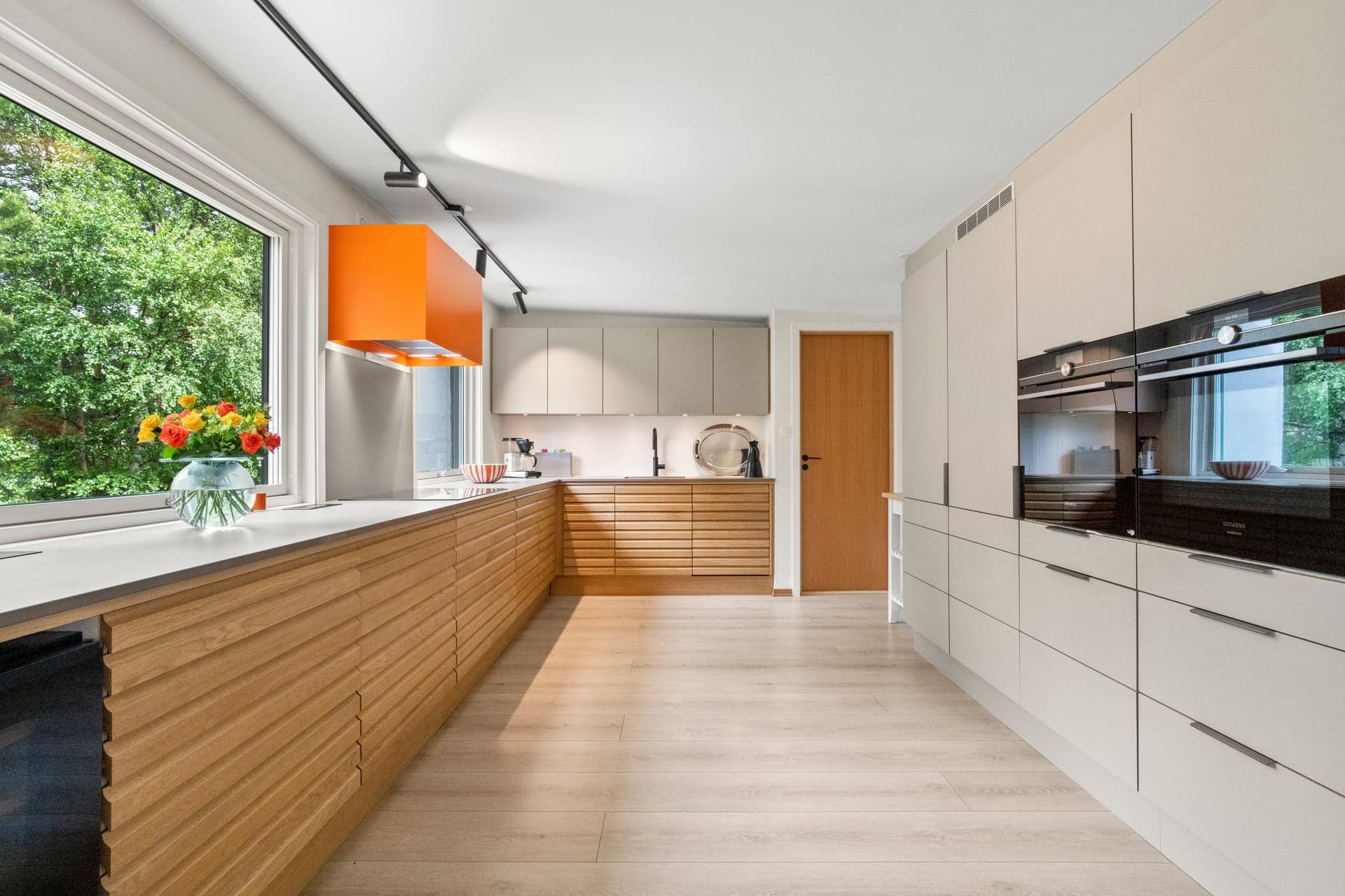 Kjøkkenet ligger separat fra stuen og fremstår stilrent og moderne, med en flott kombinasjon av trefronter med riller og beige, slette fronter.