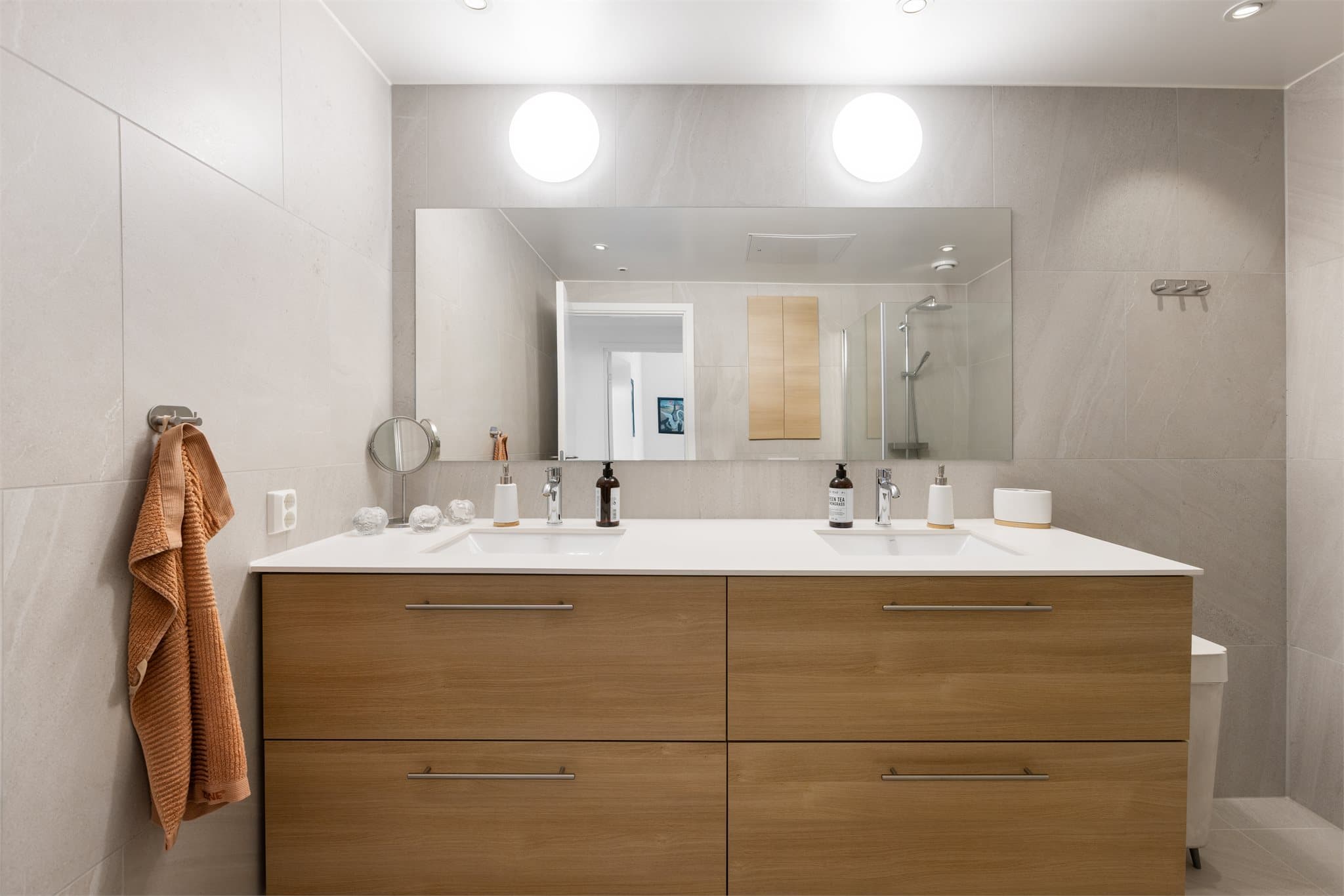 Hovedbadet er flislagt og har elektriske varmekabler i gulvet. Innredningen inkluderer en heldekkende dobbel servant på underskap.