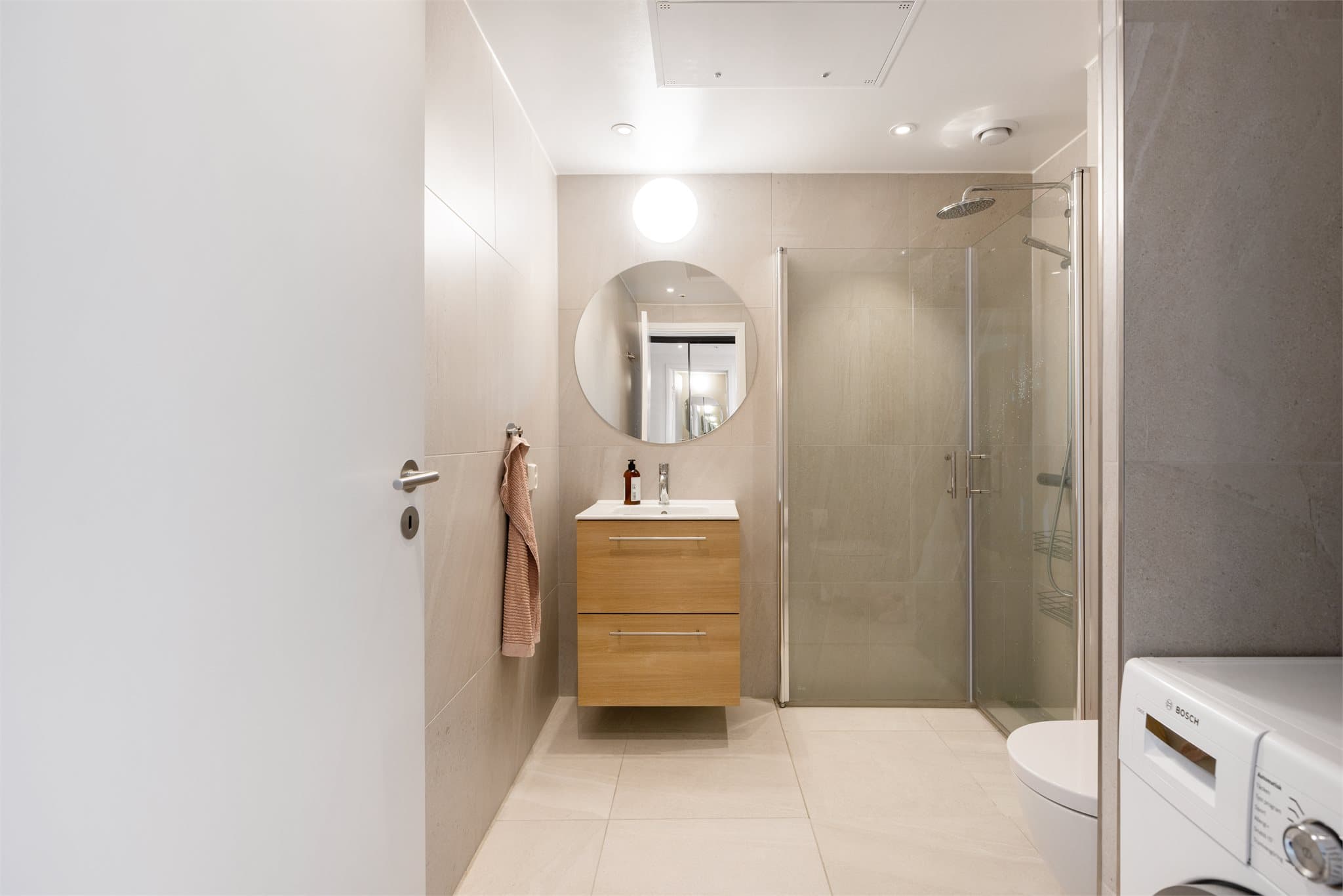 Gjestebadet har også varmekabler i gulvet, og er praktisk utstyrt med opplegg for vaskemaskin i egen nisje.