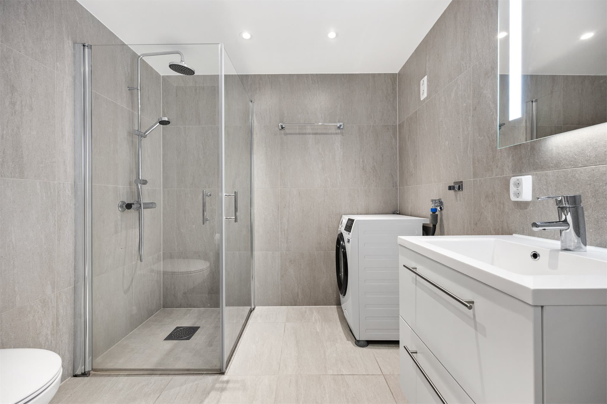 Delikat flislagt bad med downlights i himling.