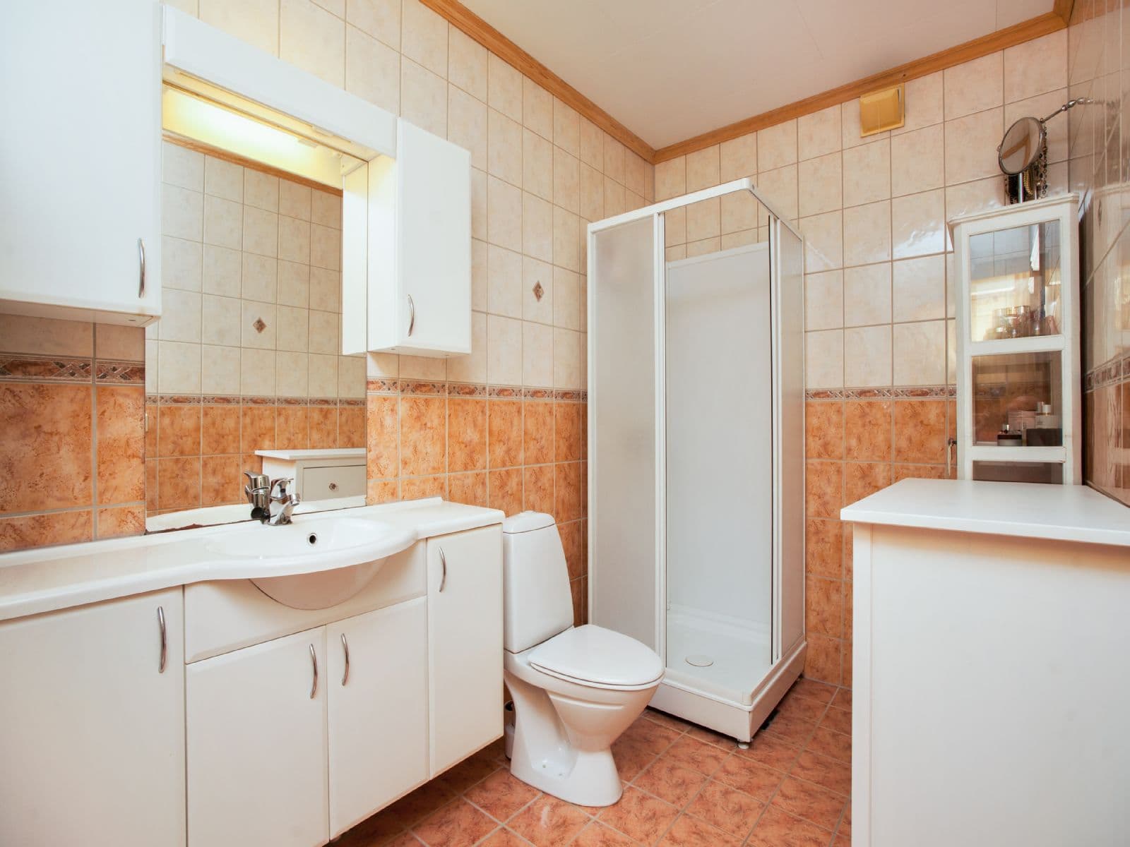 Baderom i leilighet med fliser, dusjkabinett, toalett, og servant på seksjon. Det er opplegg for vaskemaskin på badet.