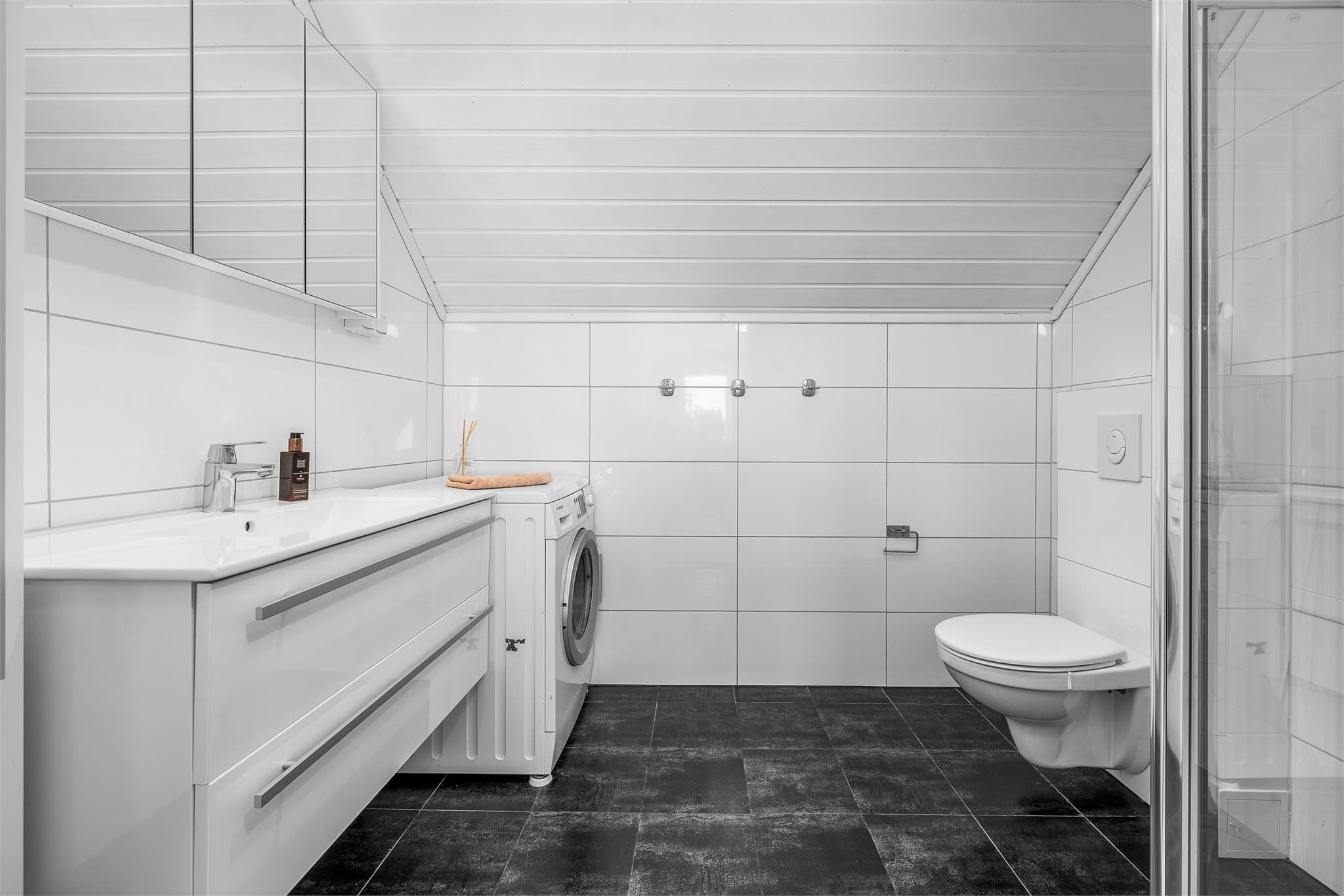 Baderom er praktisk plassert i soveromsetasjen. Her er det toalett, dusjløsning, servant på skuffeseksjon med speilskap og opplegg for vaskemaskin.