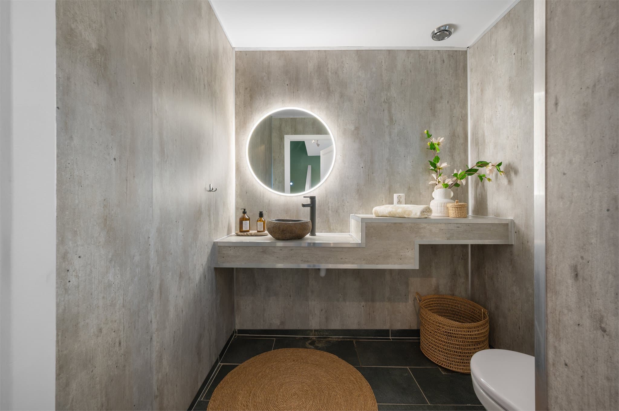 - WC måler 2,7m² og har plassbygget baderomsinnredning med toppmontert designvask i stein, speil m/belysning og toalett -