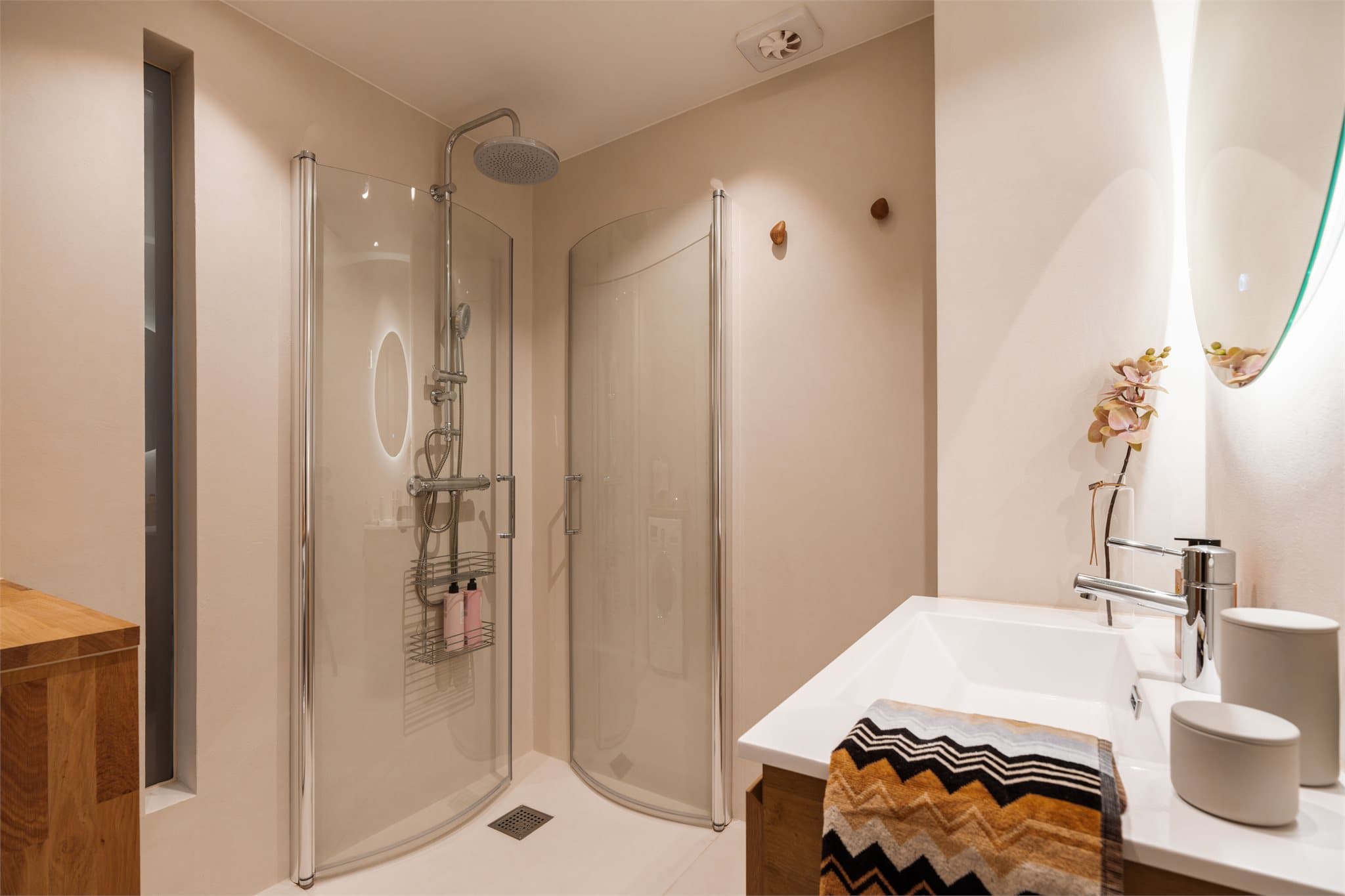 Innfellbare glassdører og regnfallsdusj gir dusjhjørnet både funksjonalitet og eleganse.