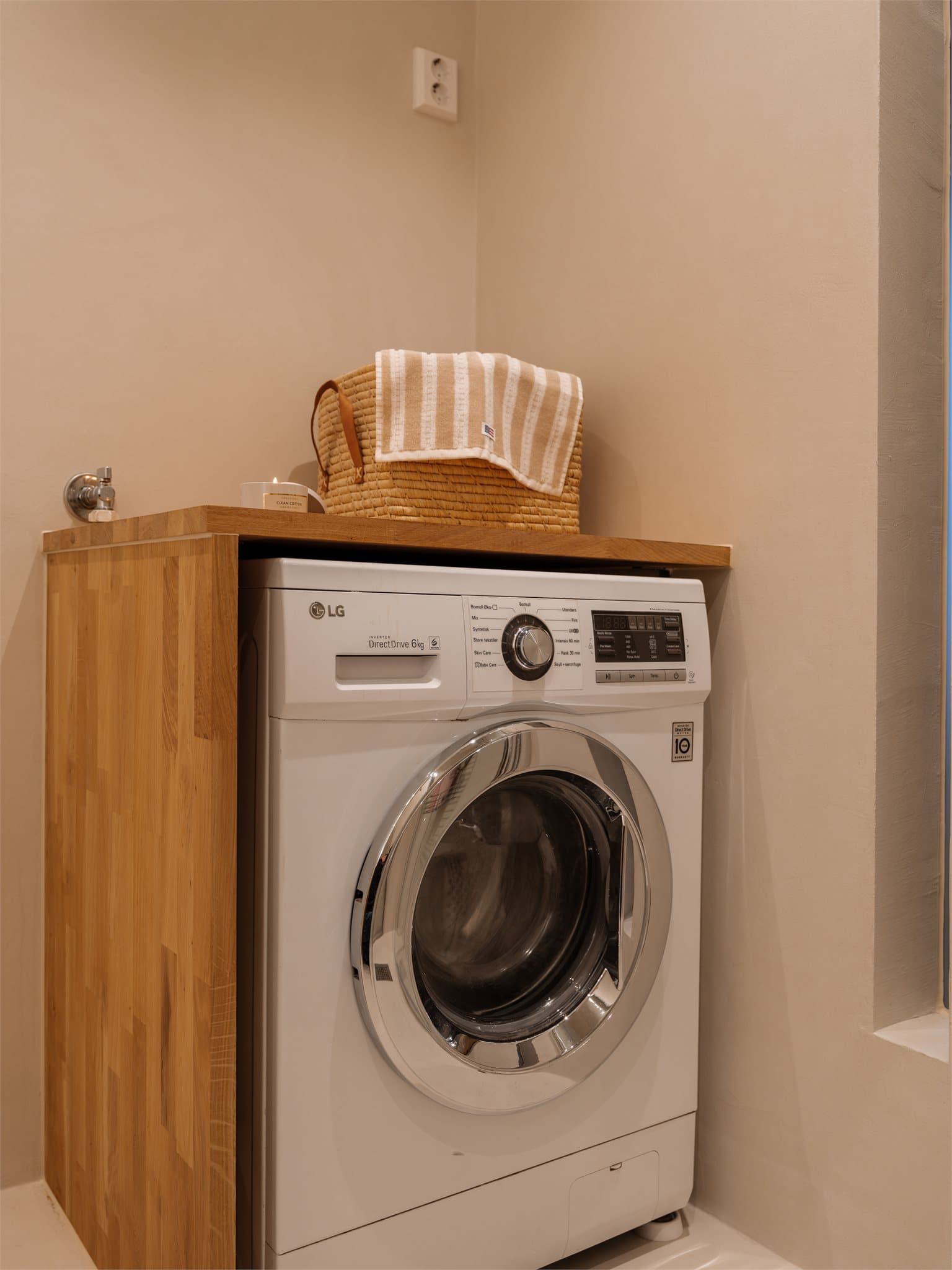 Det er praktisk opplegg for vaskemaskin på badet, med en solid benkeplate i tre. Vaskemaskinen følger med ved salg.