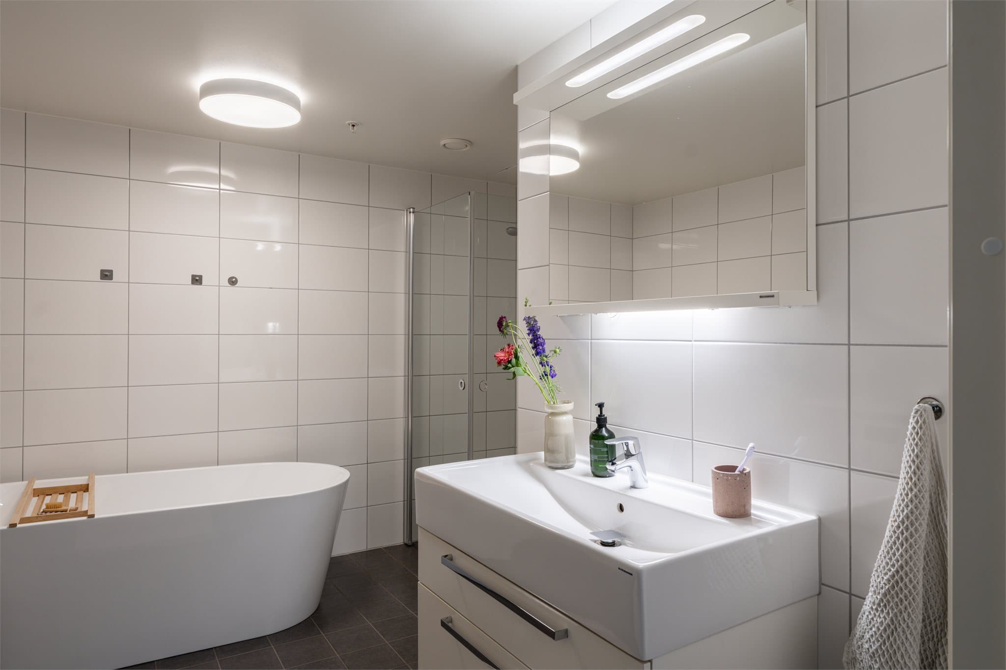 Badet har lys baderomsinnredning med integrert belysning i speilet.