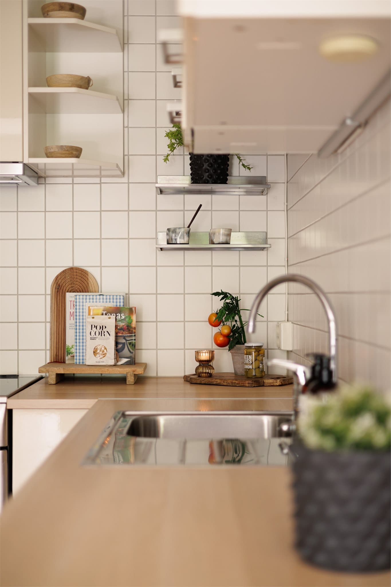 Innredningen har glatte fronter som gir et rent og moderne uttrykk, kombinert med fliser på vegg over benkeskapene. Benkeplaten i laminat har nedfelt kum i rustfritt stål.