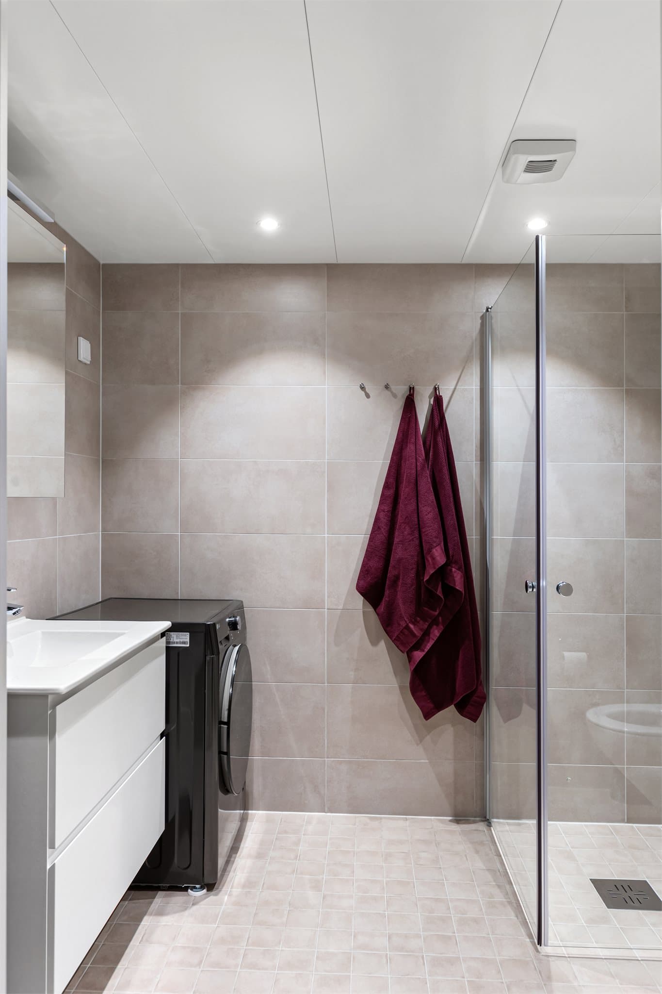 Moderne, flislagt bad fra 2024 med varmekabler i gulvet og opplegg for vaskemaskin.