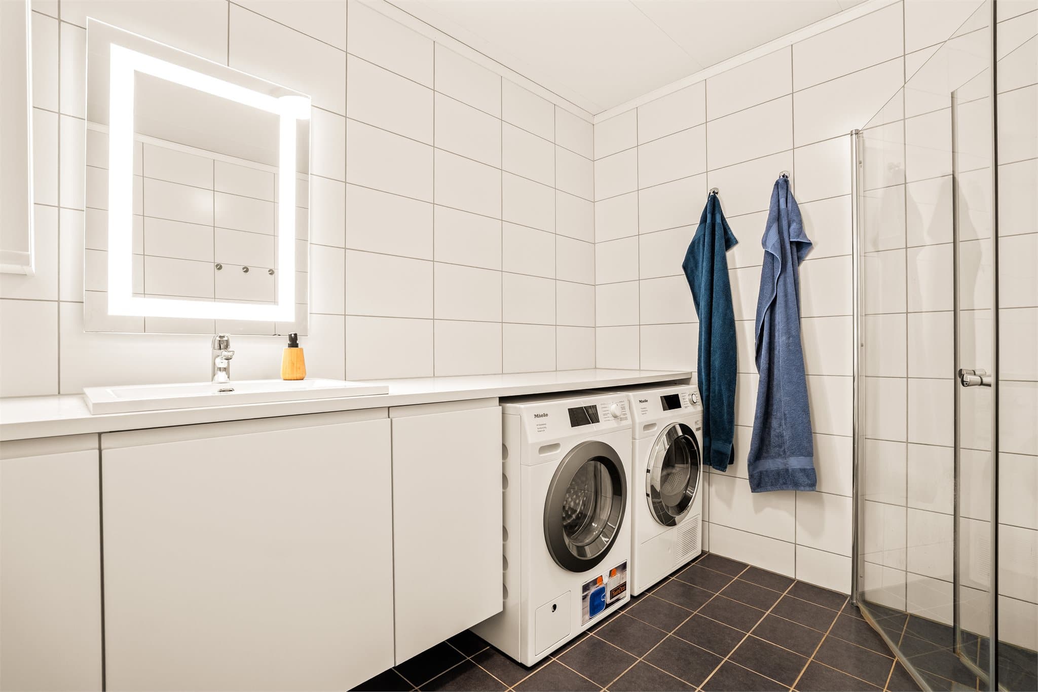 Badet er innredet med klosett, servantinnredning og dusjhjørne.