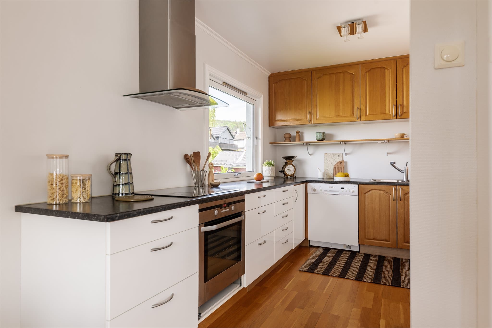 Kjøkkenet har en kombinasjon av glatte og profilerte fronter, samt benkeplate av laminat.