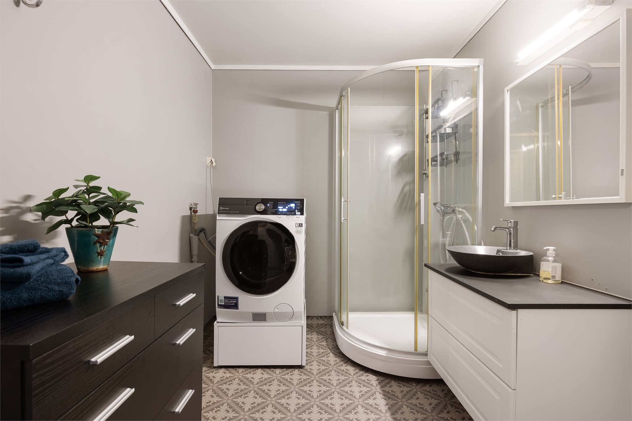 Badet måler ca. 6 kvm og er innredet med dusjkabinett, servantinnredning, toalett og opplegg for vaskemaskin.