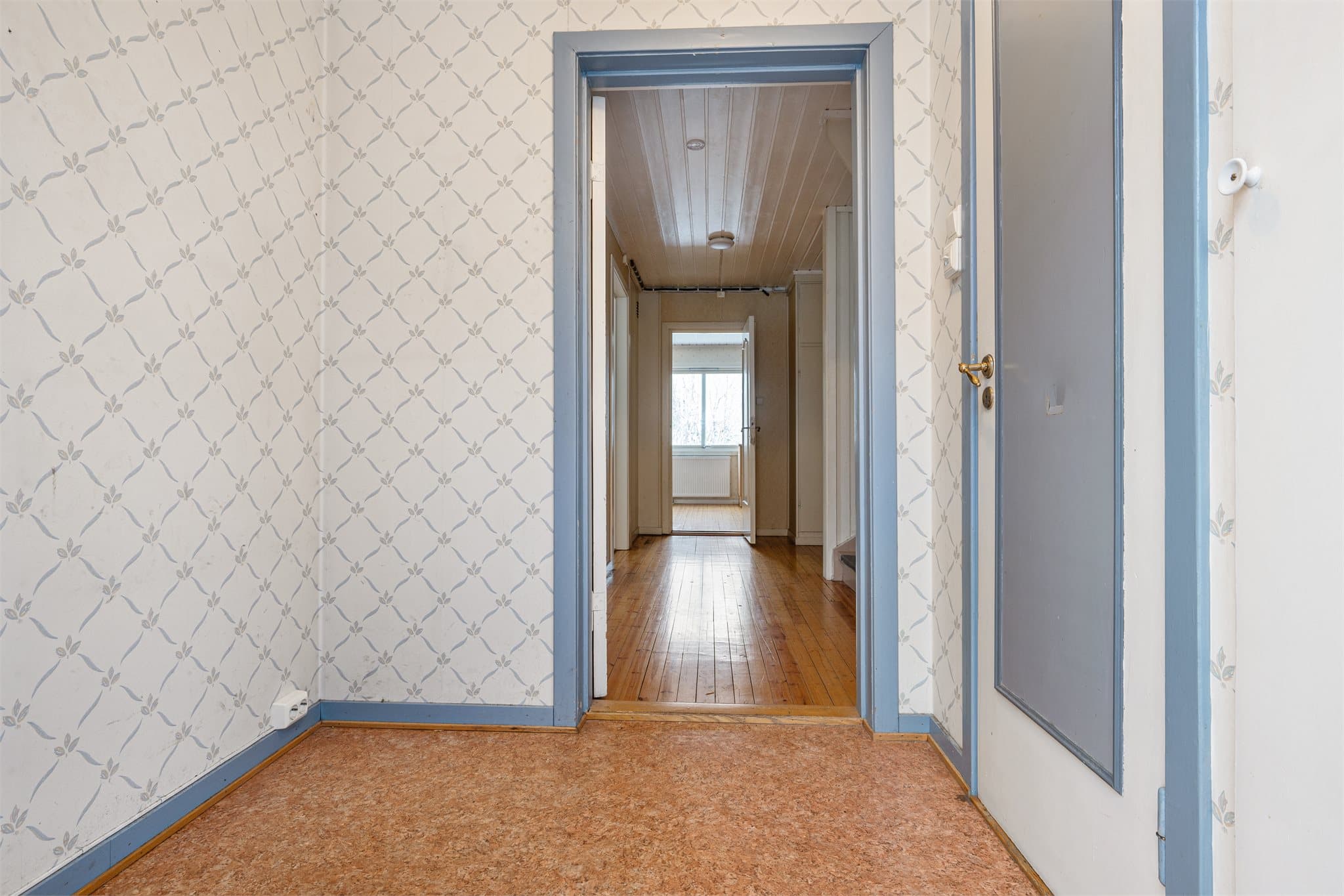 Boligens entré har belegg på gulv og tapeserte veggflater.