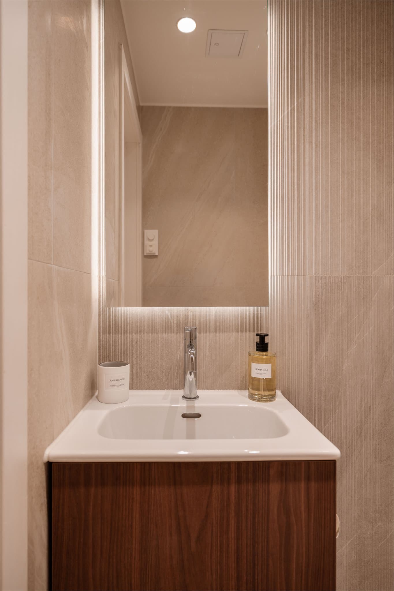 Toalettrommet er innredet i samme stil som badet, med servant og speil med integrert lys.