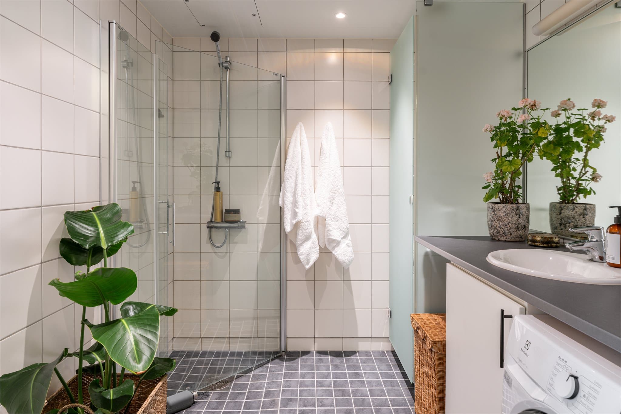 Badet har flislagte overflater og gulvvarme, samt et praktisk tørkeskap som gir en smart løsning i hverdagen.